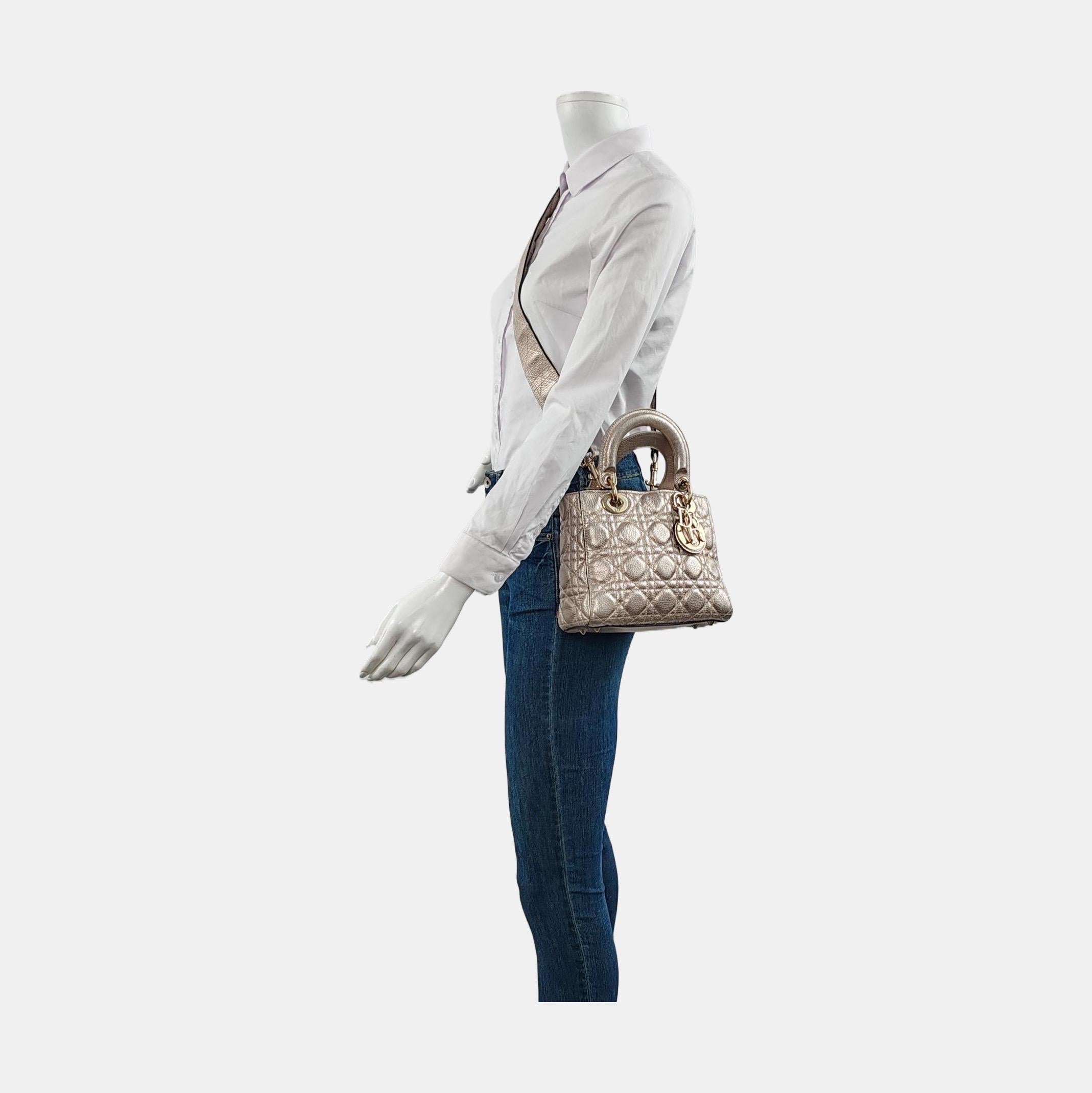 This Lady Dior Mini Supple Calfskin Leather Gold Cannage Handbag with Strap is crafted from supple calfskin leather and features a unique cannage stitch. Unlike the iconic Lady Dior, this version has a more casual look due to its intentionally
