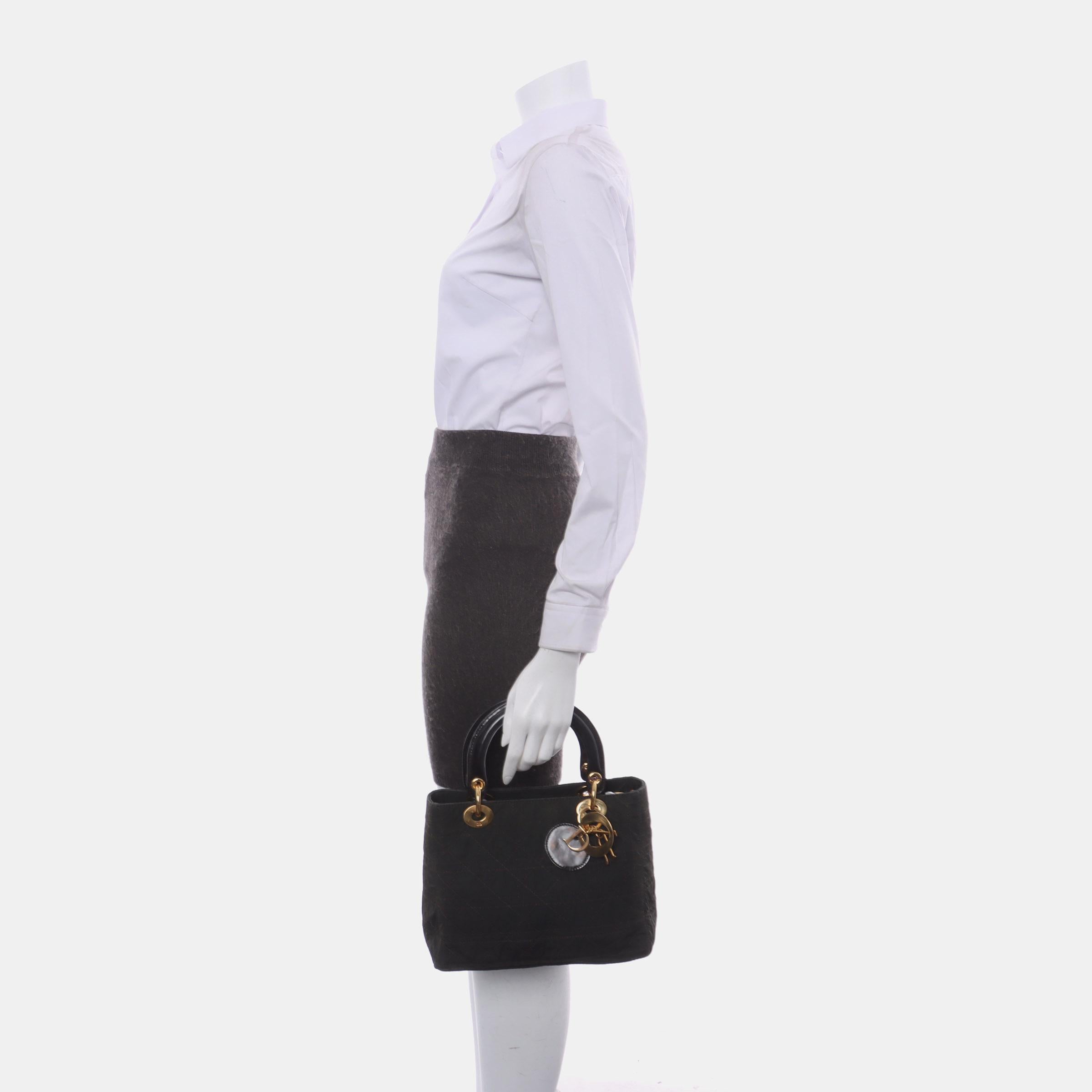 This large Lady Dior handbag, made of high-quality black cloth with iconic micro-cannage stitching, is a stylish and elegant accessory for your wardrobe. It is adorned with contrasting yellow gold-toned hardware, which is still in excellent