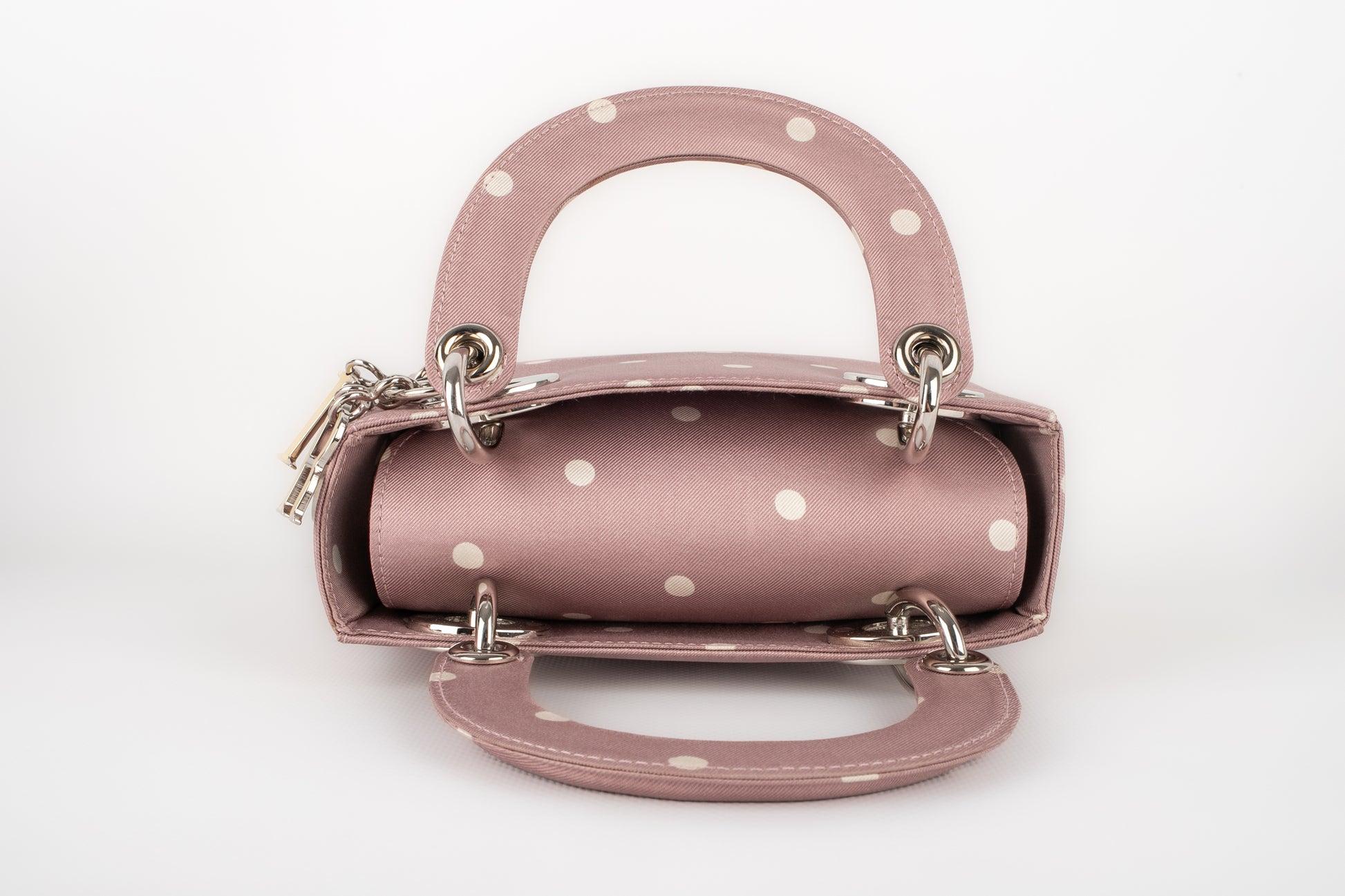 Dior - (Made in Italy) Lady Dior mini bag made of mauve silk with white dots, and with enameled silvery metal elements. Piece sold with a serial number and a certificate. 1997 Collection.

Additional information:
Condition: Very good