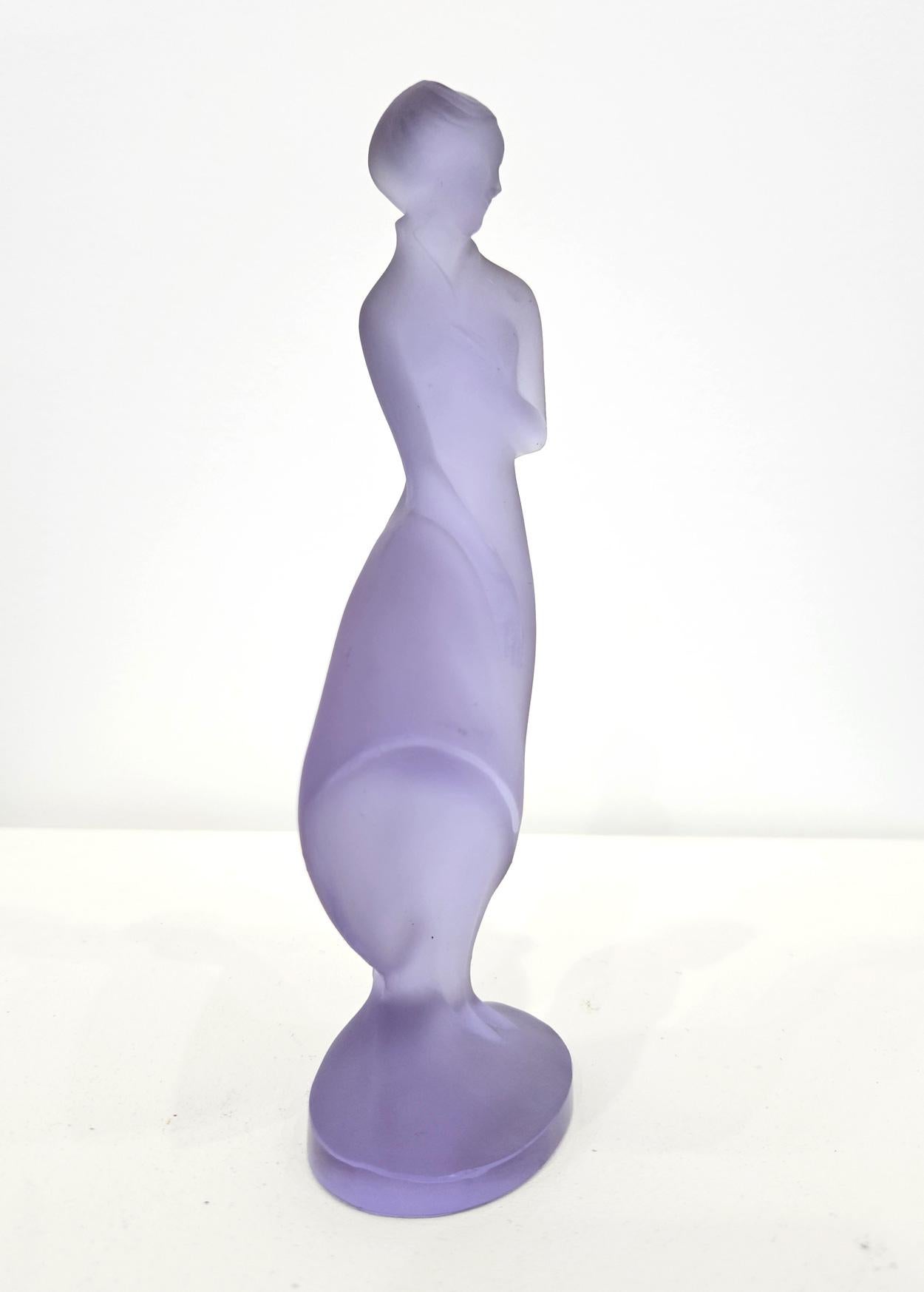 A Czech Bohemian ‘Lady in the Wind’ lilac glass figure, made in c. 1937 by Curt Schlevogt and designed by Ida Schwetz-Lehmann. 

This moulded glass figures comes from Schlevoght’s ‘Ingrid’ series, unveiled at the Spring Fair in Leipzig in 1934 and