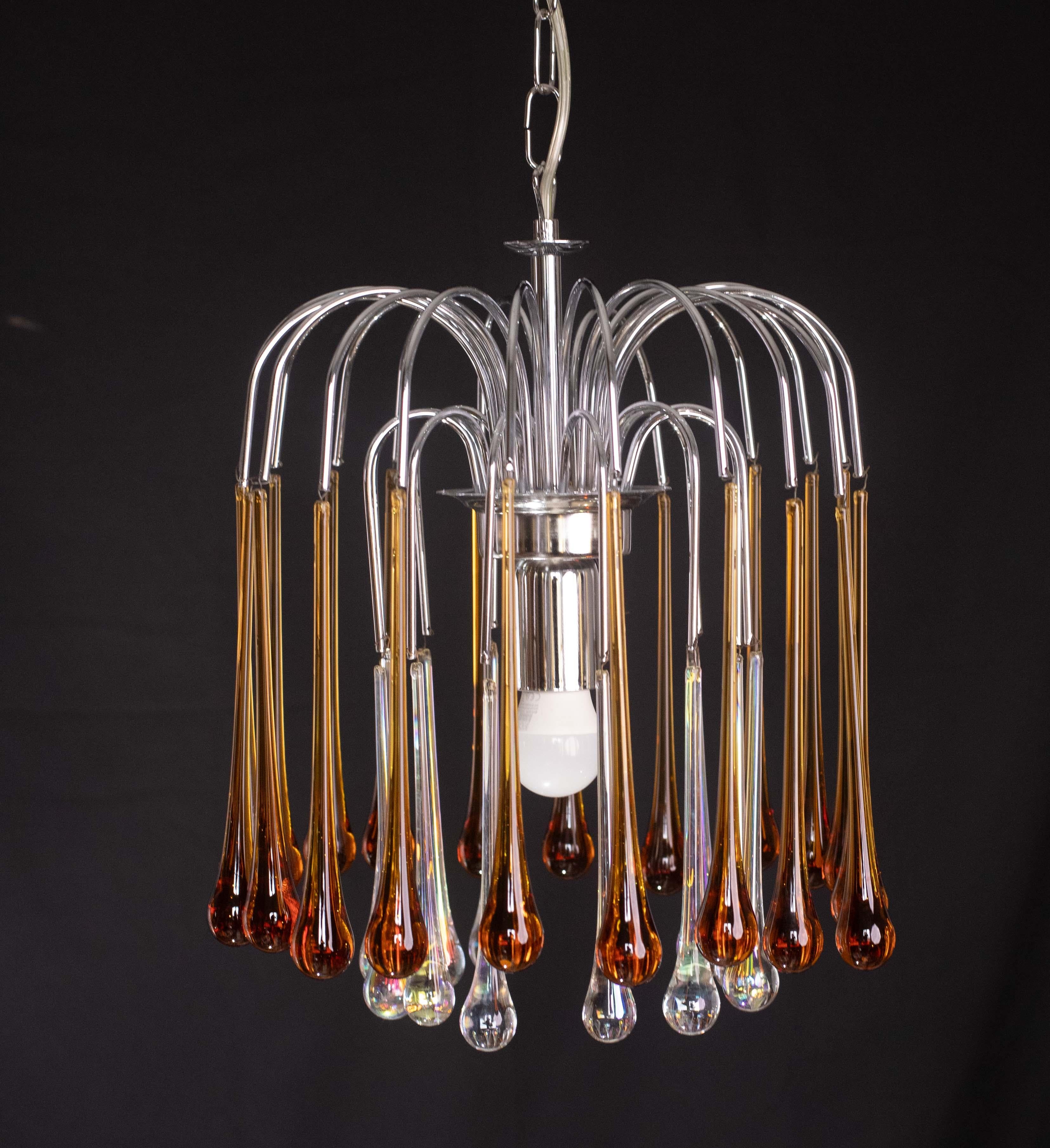 Stupendo lampadario di Murano nello stile di Venini La Cascata.
Il lampadario è composto da due tondi composti da bellissime gocce iridescenti che sono trasparenti all'interno e ambrate all'esterno, 10 gocce all'interno e 20 all'esterno; la