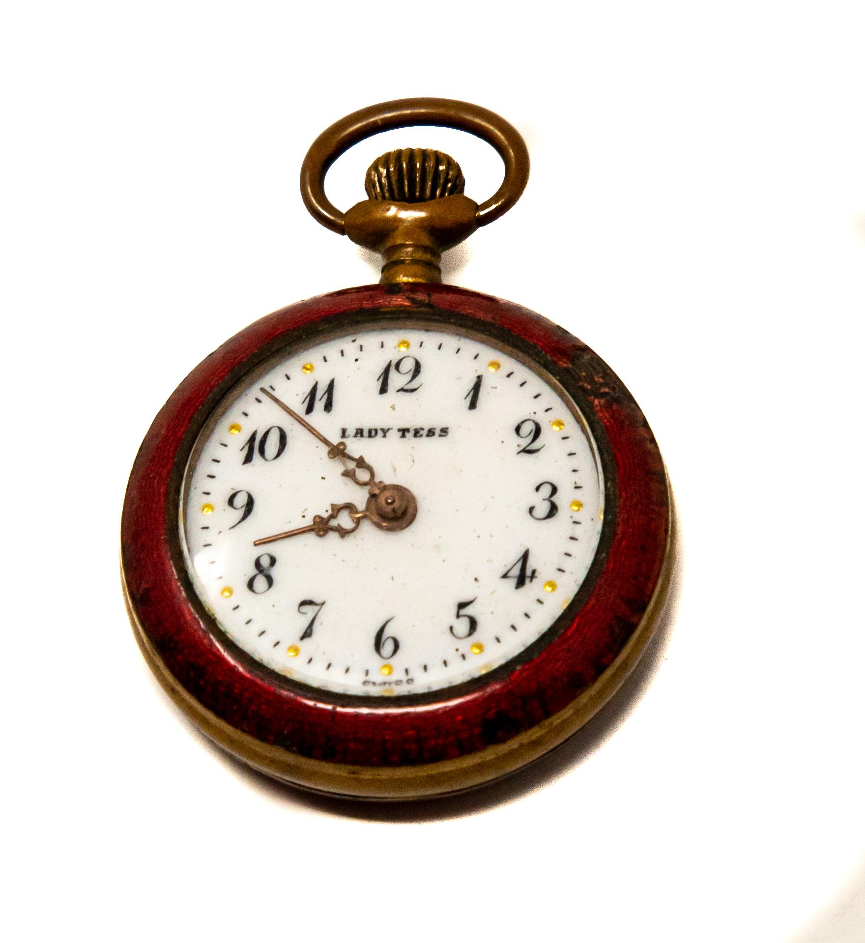 Offering this sweet little ladies pocket watch. Marked Lady Tess on the face of the watch and on the bottom marked Swiss. Having red enamel around the face and over the back of the brass body.