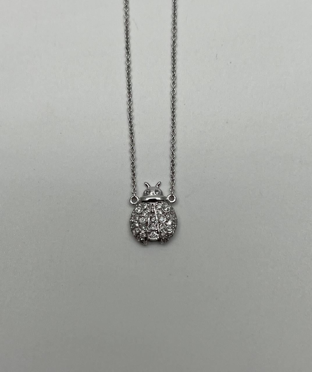 Este exquisito collar está elaborado en oro blanco de 18 quilates. El colgante presenta un encantador diseño de mariquita adornado con brillantes diamantes blancos. Los intrincados detalles y la fina artesanía realzan la belleza de la pieza,