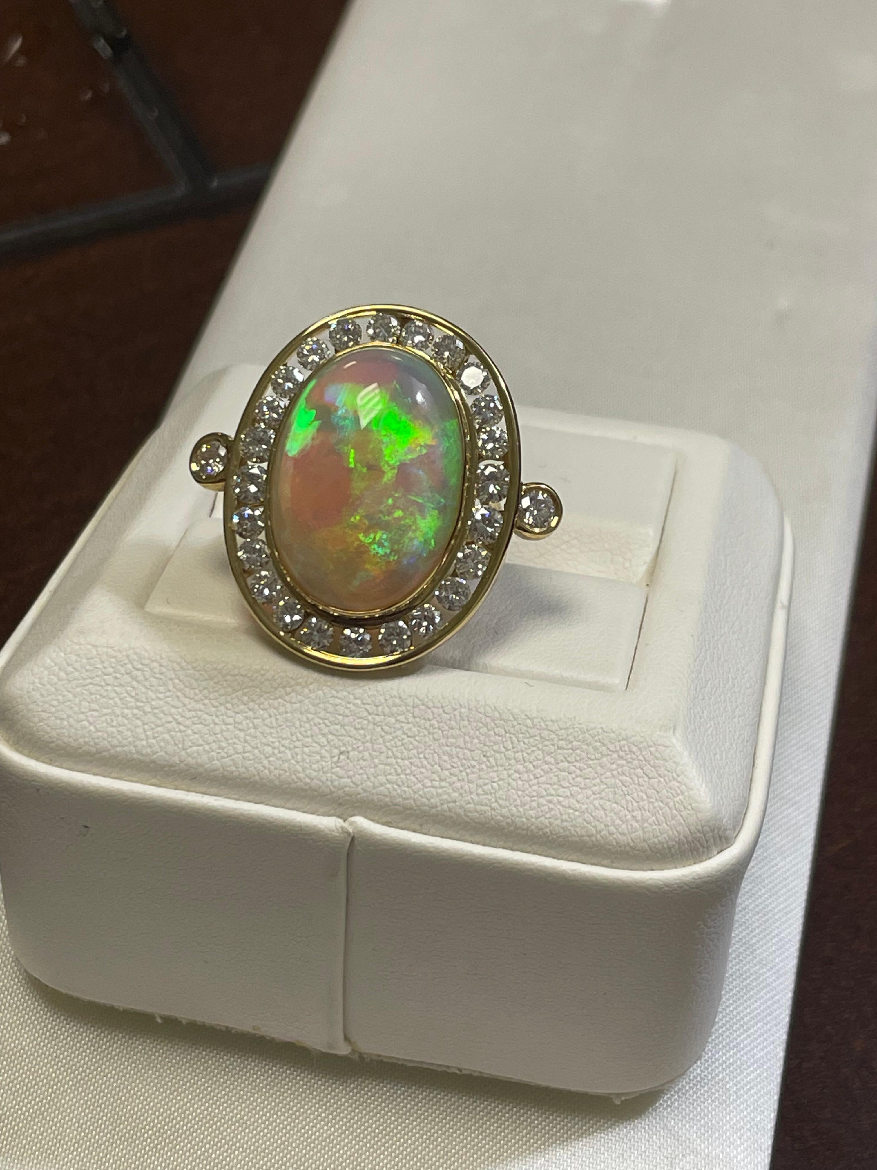 One lady's black opal in crystal white.  Multicolor fire pattern with an average saturation scale. Very bright with flash fire pattern.  Cabochon, oval shape.  Measurements are 21.0 x 15.0 mm.  Weight is 14.5 carats. 27 round brilliant-cut diamonds.