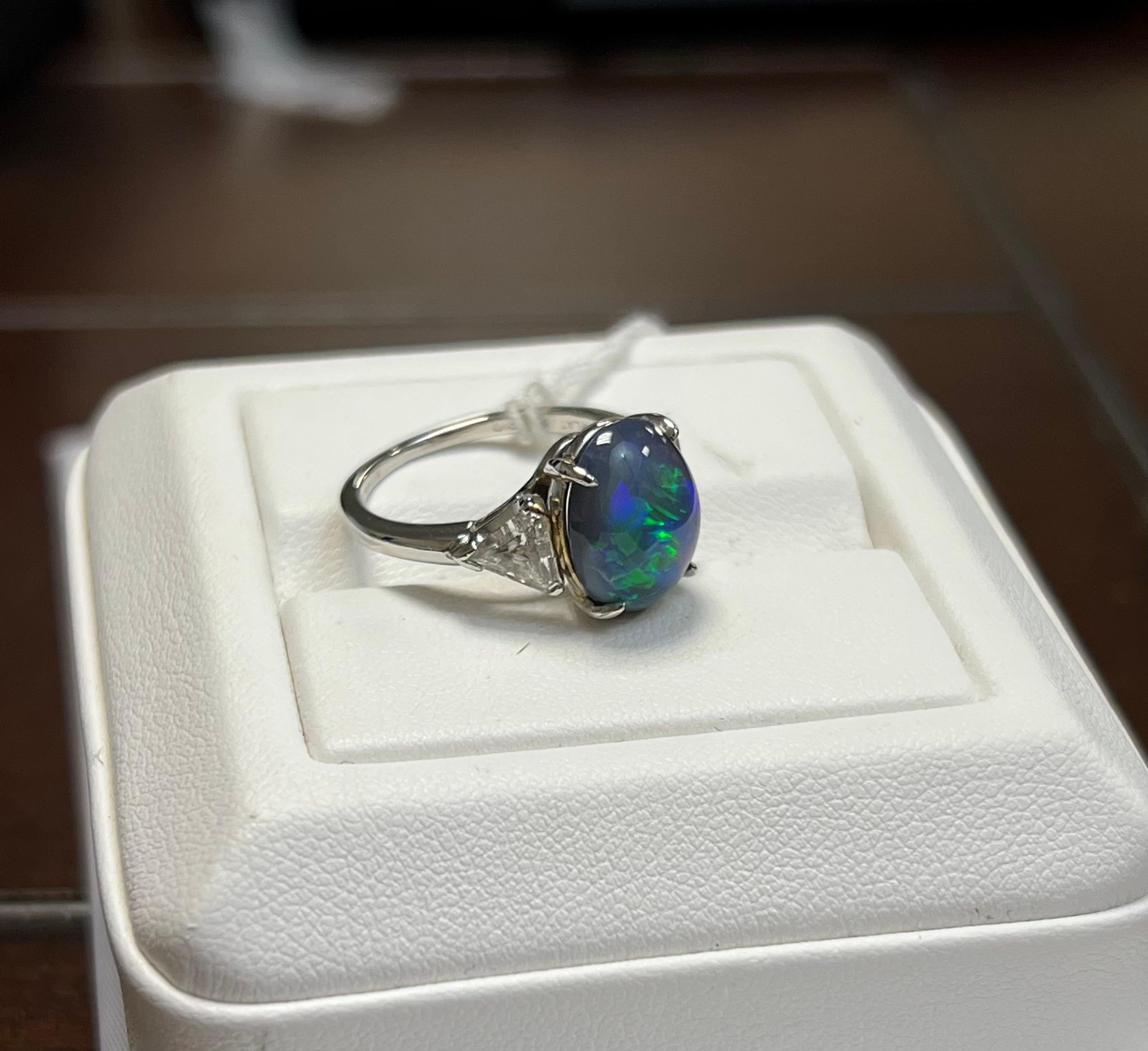 L'opale noire d'une dame en couleur bleu-vert de feu. Échelle de saturation vive avec motif de feu flash. L'éclat du feu est très brillant avec le cabochon, de forme ovale. Deux diamants taillés en forme de trillion mesurant 5,0 x 5,25 mm. Le poids