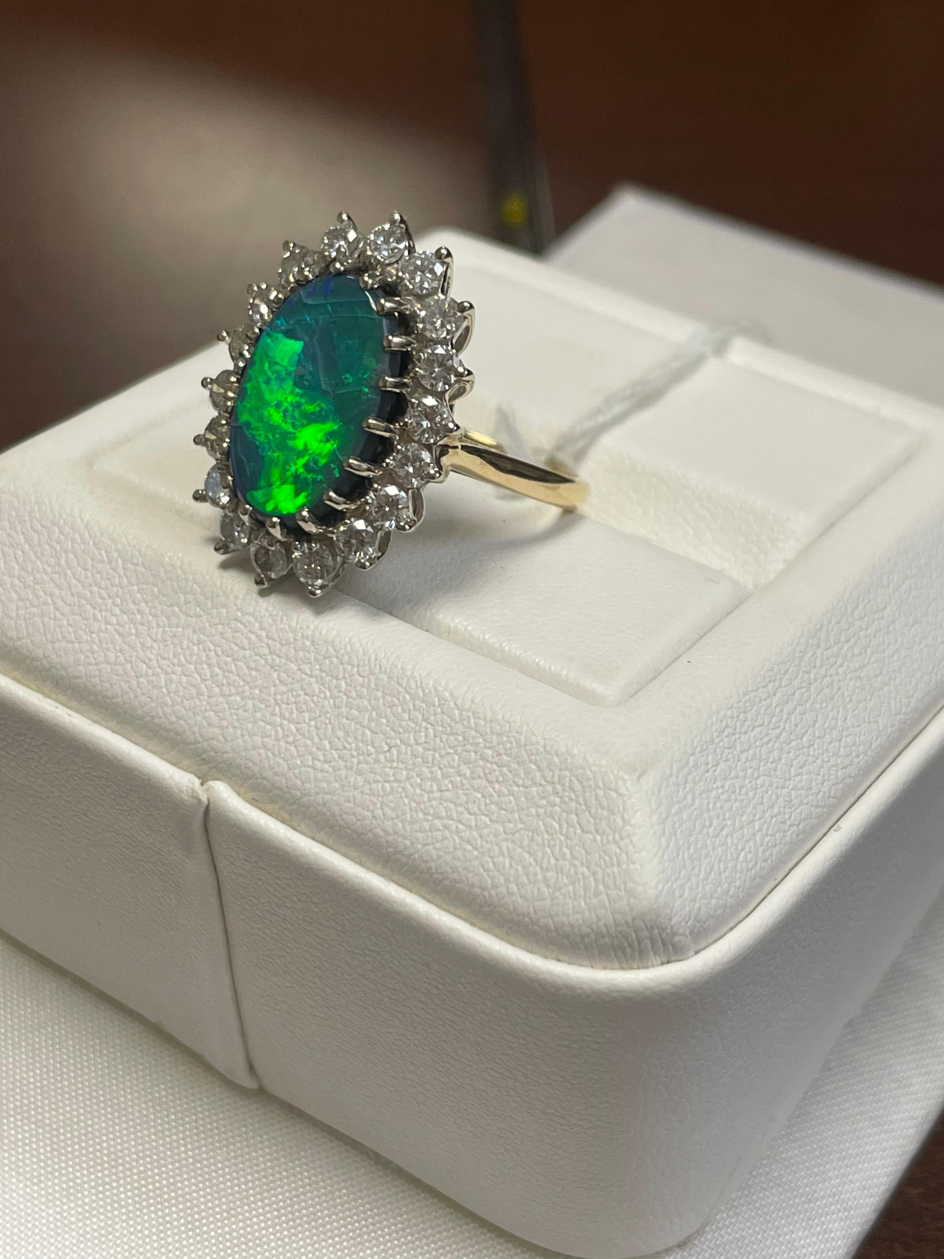 One lady's black opal in blue-green fire color with an average saturation.  Contains a very bright pinfire pattern.  Cabochon, oval shape.  Condition is crazed.  Measurements are 15 x 10.00 mm. Weight is 3.5 carats.  18 round brilliant-cut diamonds.