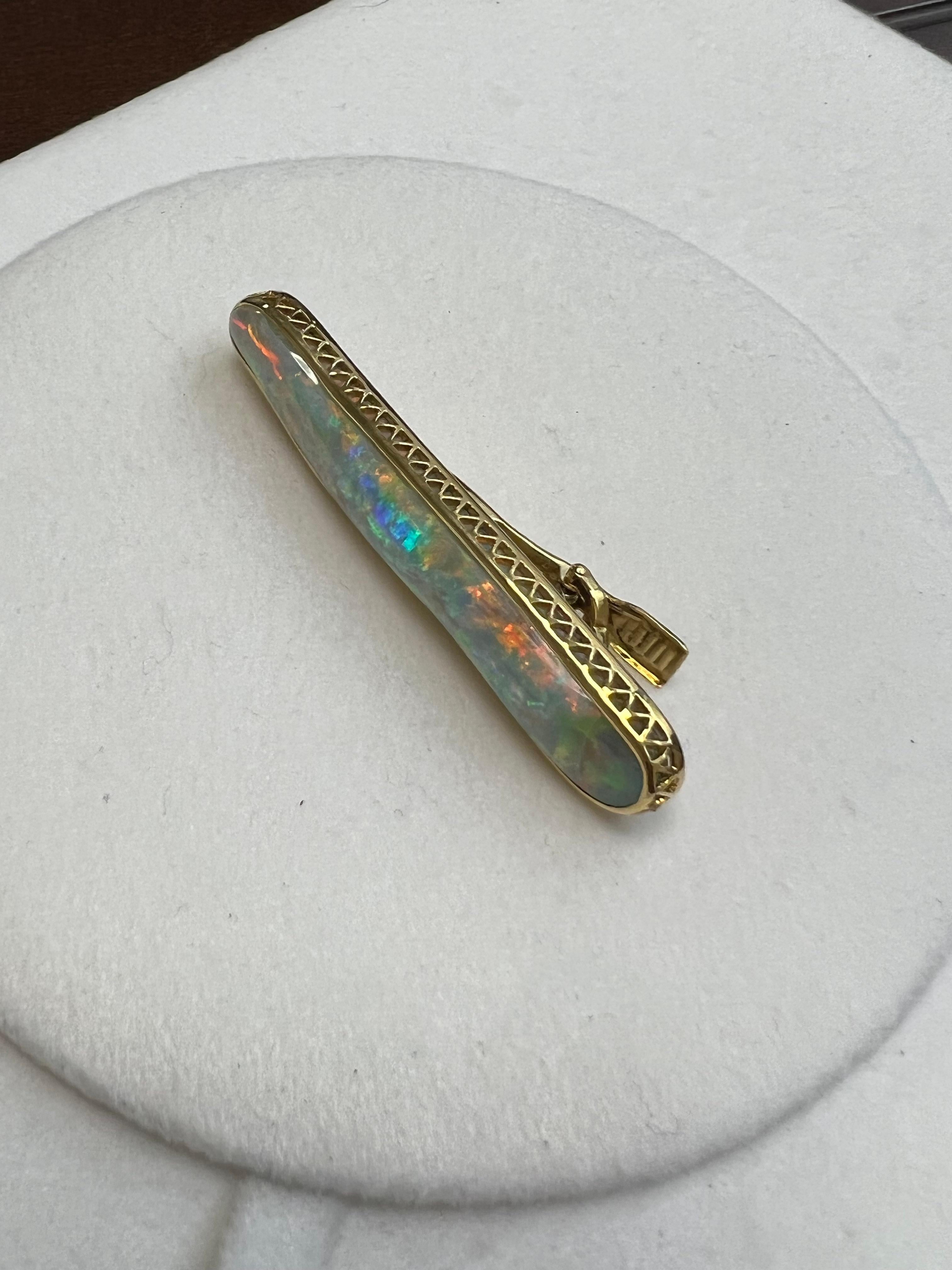 One lady's boulder black opal in a multi-color fire color. Vivid saturation scale with flash fire pattern. Brightness of fire it quite bright with cabochon, freeform shape. Measurements are 55 x 10. Broach is hand made in 18k yellow gold. Gross