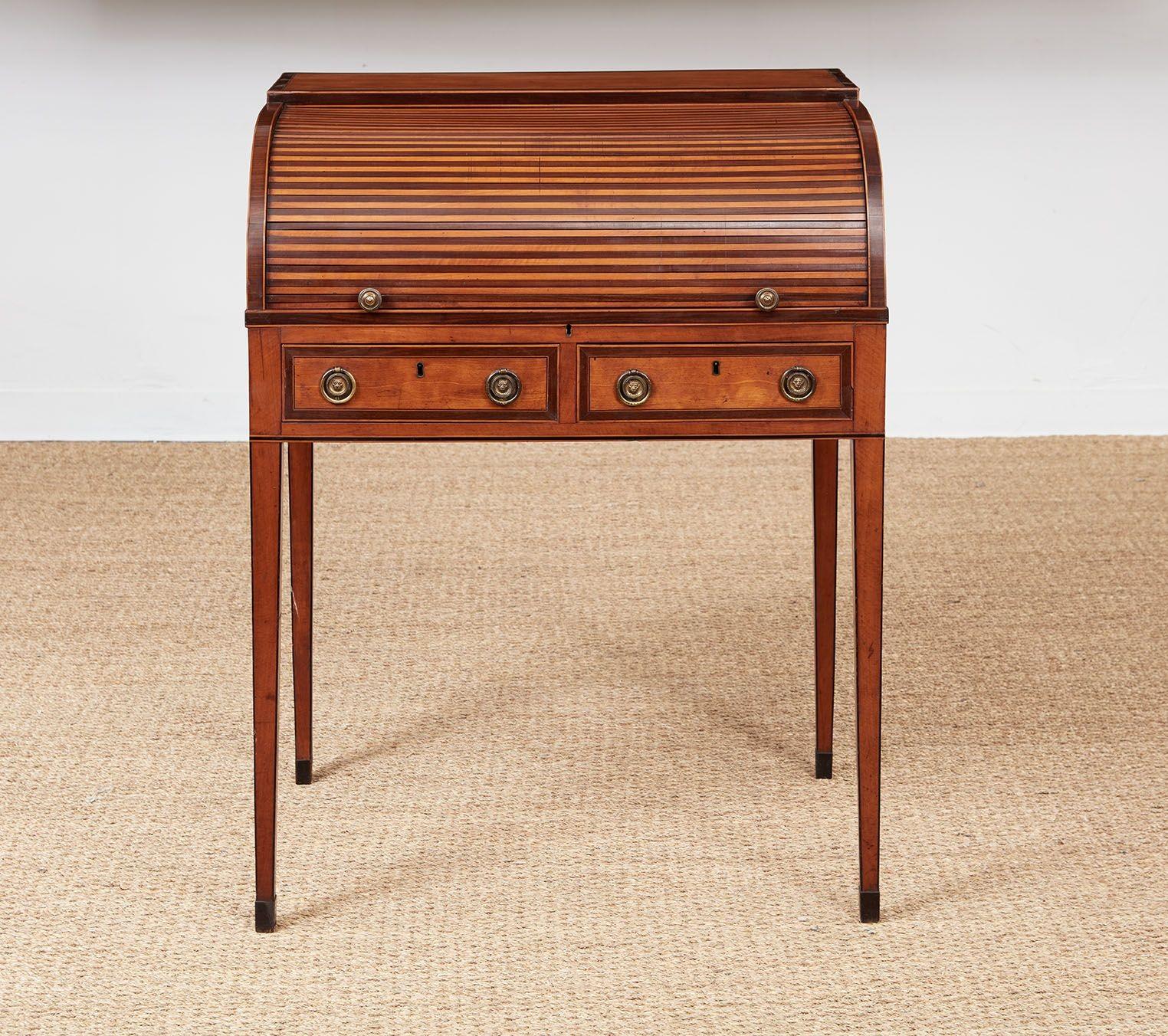 A smart and tailored Sheraton correspondence desk in figured satinwood having a multi-drawer casement with letter slots covered by a retractable curved tambour door in alternating strips of satinwood and rosewood, over two rosewood crossbanded