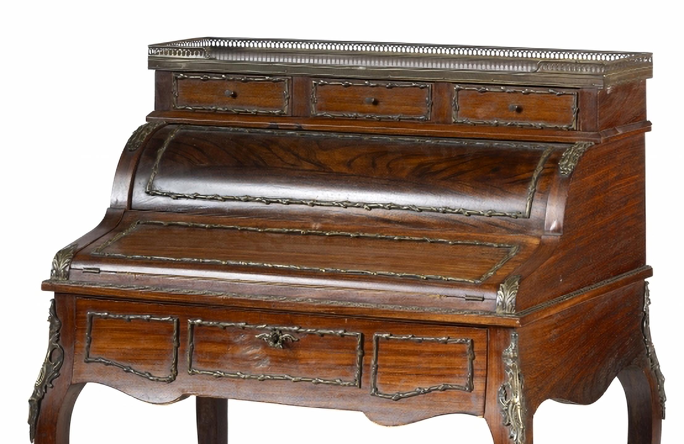ESCRITORIO DE SEÑORA CON TAPA CILÍNDRICA

Francés del siglo XX, estilo Luis XVI,
madera de caoba.
Elevado con tres cajones, encimera enrollable, interior con cajones y compartimentos, y parte superior deslizante forrada de tela.
Asas y herrajes de