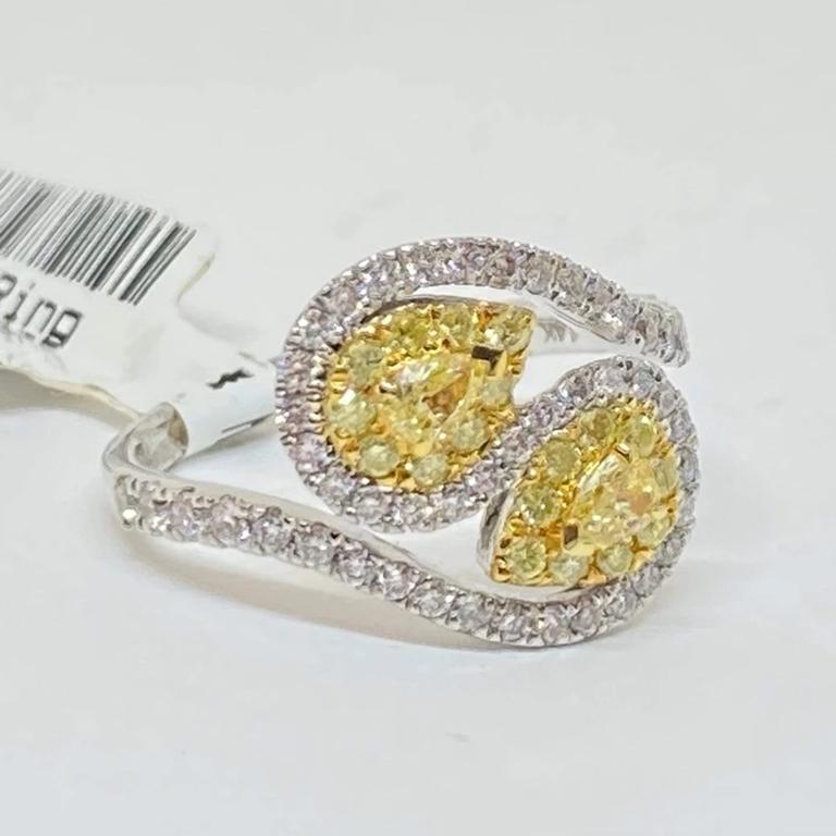 Beautiful fancy yellow and white diamond right hand ring designed in 14 karat white and yellow gold. The ring contains two main pear shape fancy yellow diamonds in a swirl bypass motif. The two main fancy yellow diamonds weigh .23 carats total