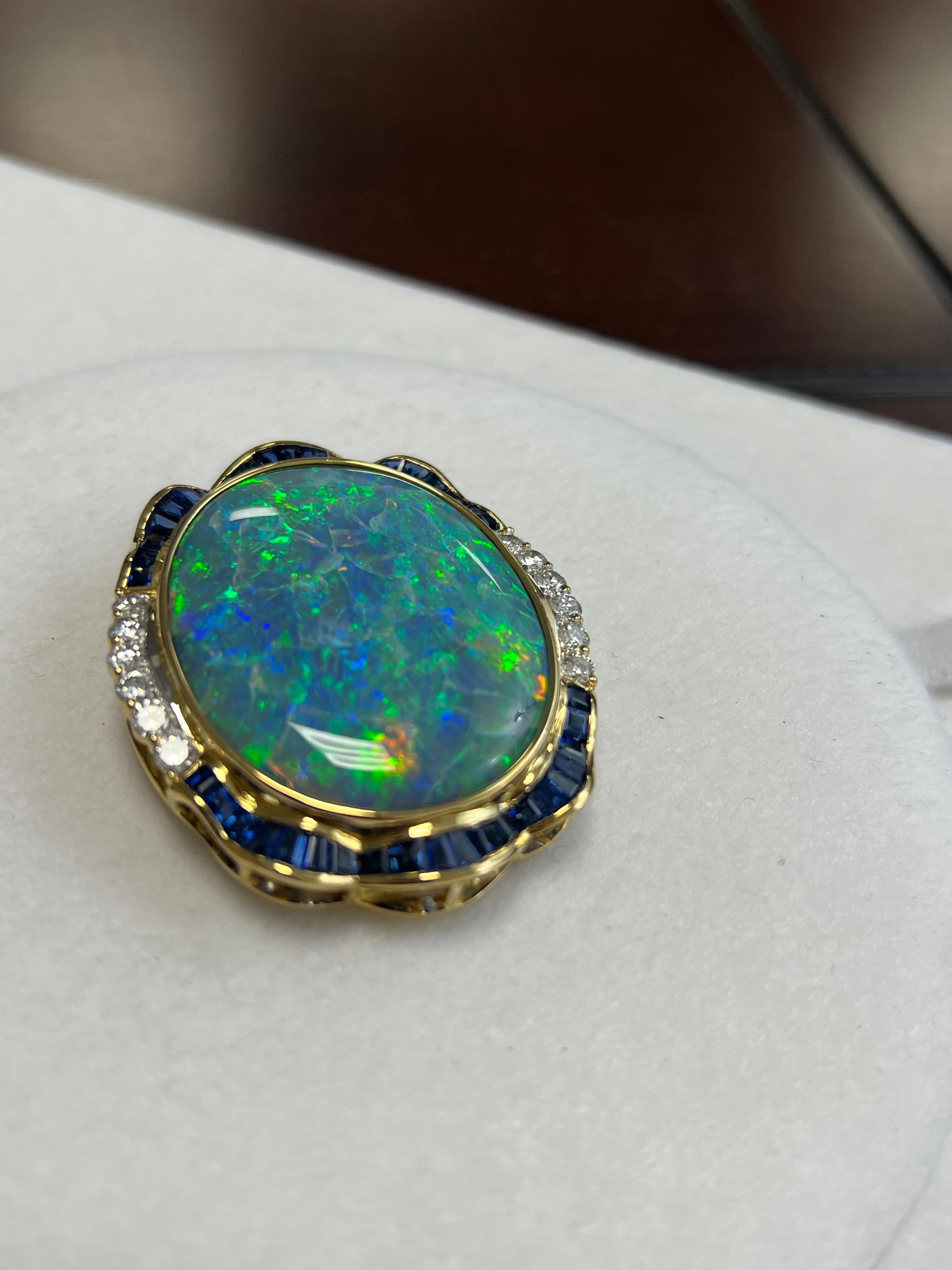 One lady's black opal in blue-green fire color. Vivid saturation scale with flash fire pattern. Brightness of fire is extremely bright with cabochon, oval shape. Measurements are 40.0 x 32.0 mm. Weight is 91.0 carats. 40 baguette blue sapphire.