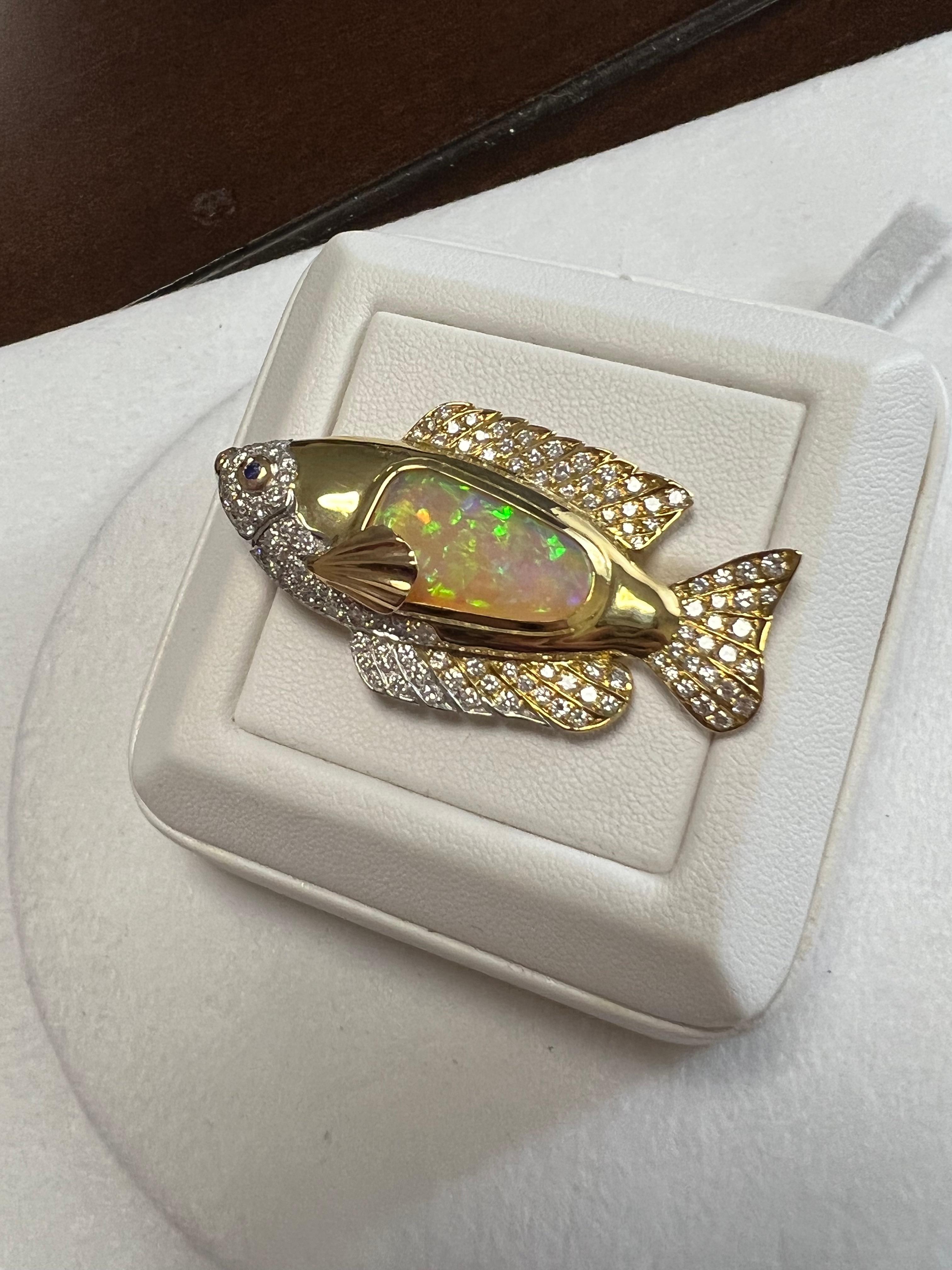 One lady's custom designed and fabricated semi-black crystal opal fish that is multicolor. Average saturation scale with flash fire pattern. Brightness of fire is somewhat bright with cabochon, freeform shape. Measurements are 18 x 10.5. 96 round