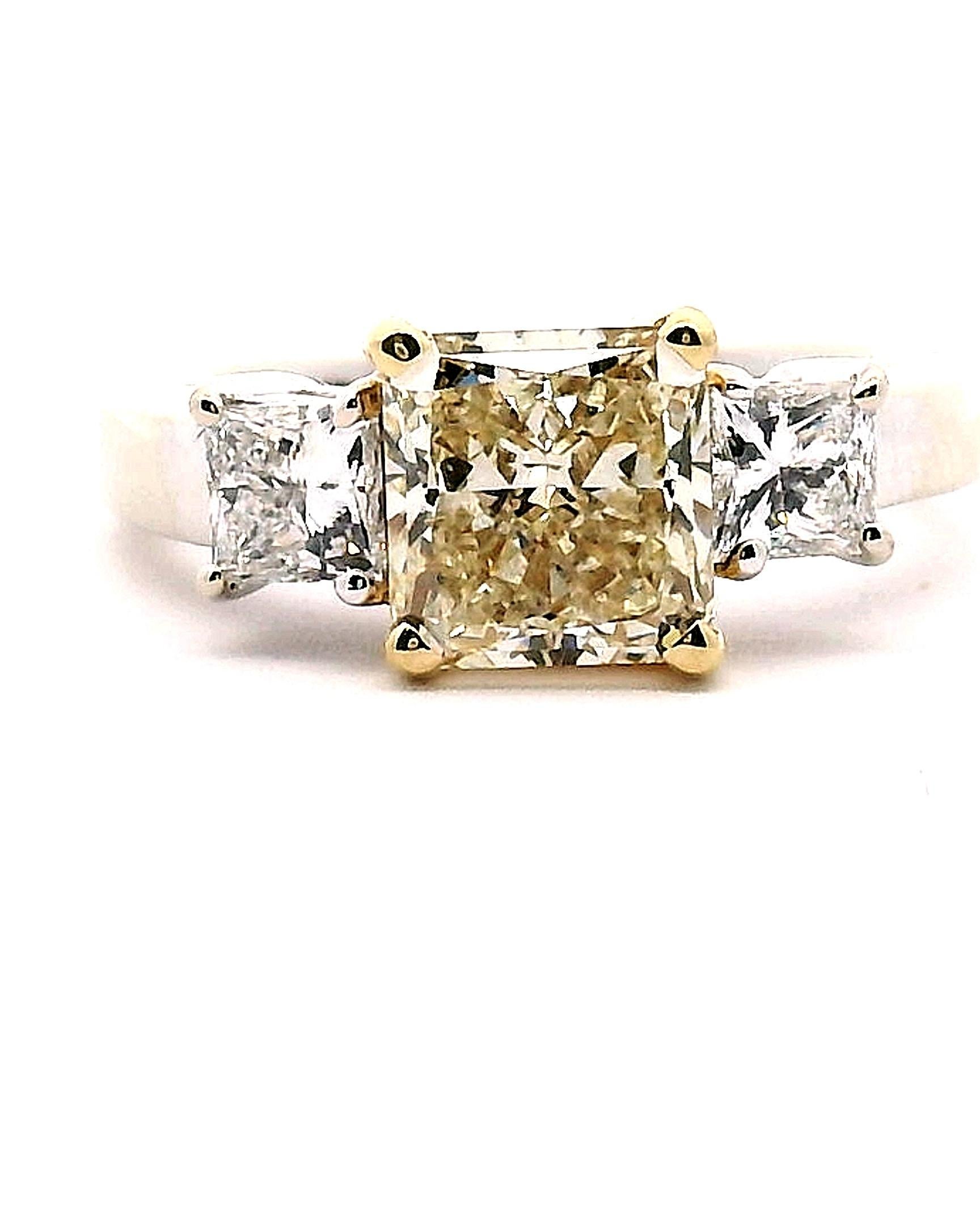 Lady's white & yellow gold engagement ring with three princess cut diamonds 1 fancy yellow & 2 white diamonds. 

Center diamond approximately 2.01ct.

Clarity grade is VS1 
Color grade is Lite Fancy yellow 

Side diamonds approximately .80 cttw.