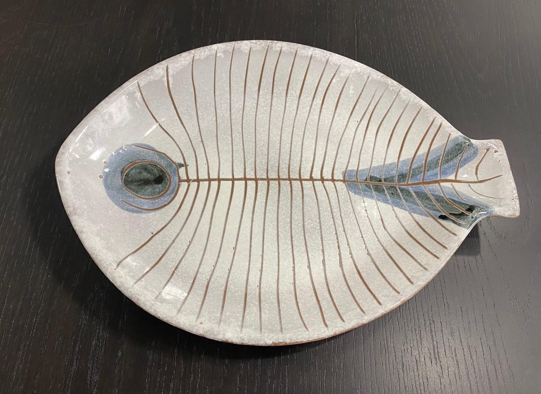 An iconic, beautifully designed, and decorated fish plate/ platter by famed Mid Century designers LaGardo Tackett (the primary founder of “Architectural Pottery,”) and Kenji Fujita and features their very distinctive glazing technique. 

This
