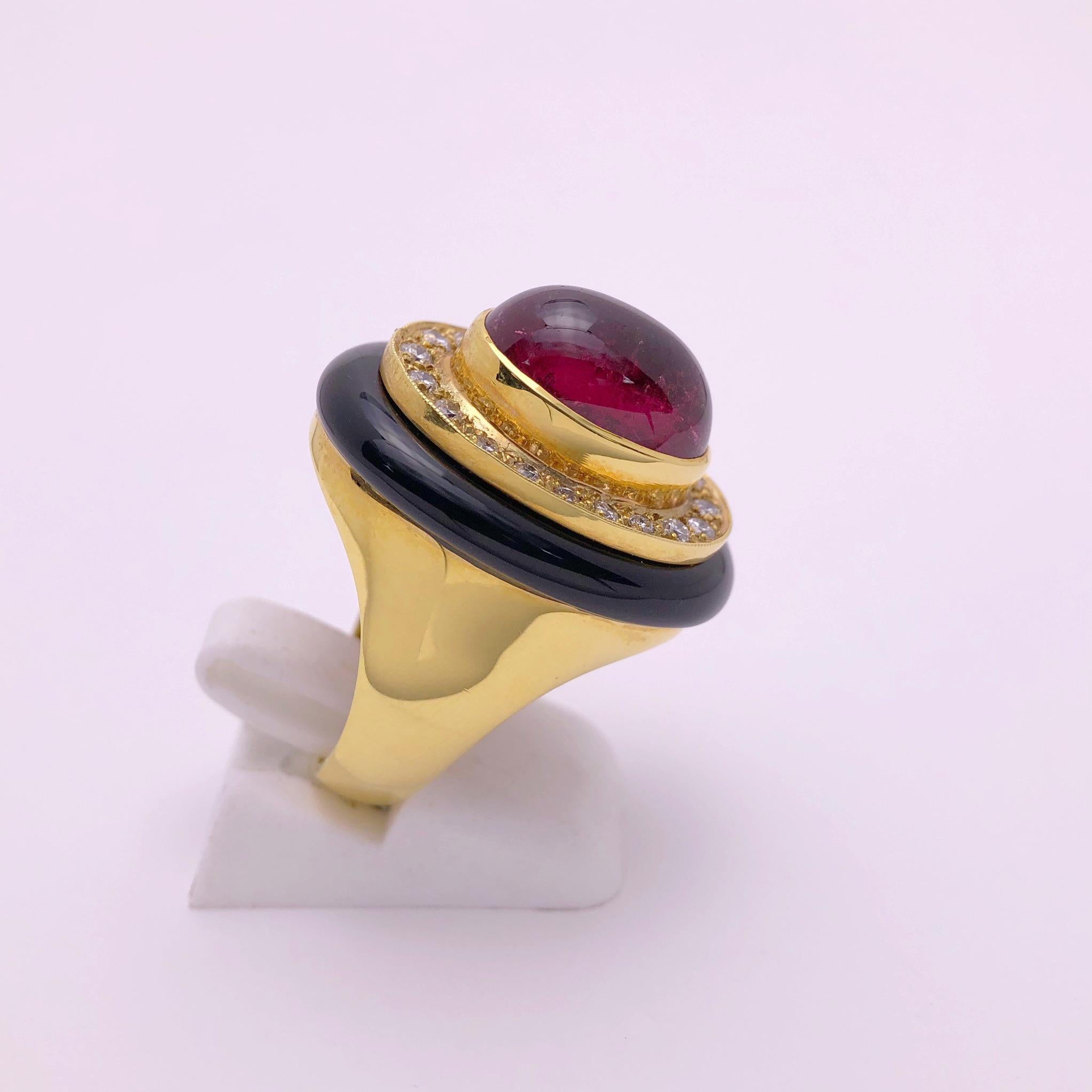 Crafted by Lagos, This 18KT Yellow Gold  ring centers an oval cabochon pink tourmaline. There are 20 round brilliant diamonds surrounding the center tourmaline, and a ring of black onyx surrounding the diamonds. The shank of the ring is a