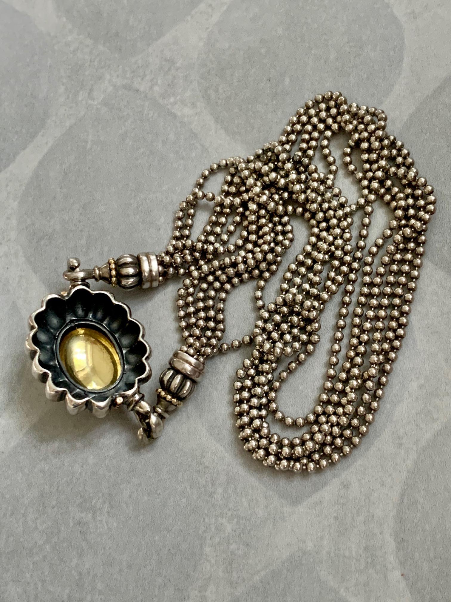 This signed Lagos Caviar Sterling and 18 Karat Yellow Gold features a pendant measuring 32 x 29mm.  The chain is a six strand bead chain.

Weight: 74.2 grams
Necklace Length: 18