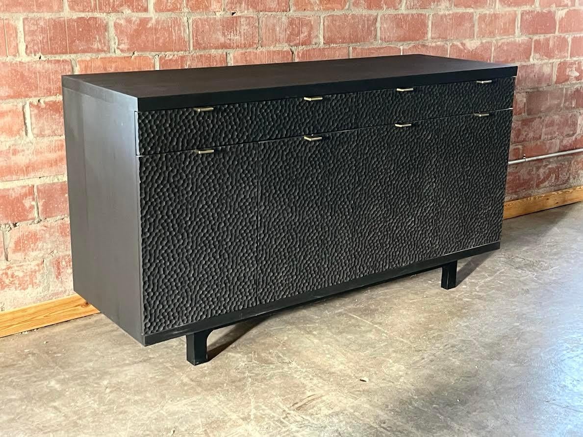 The Laguna collection dimple sideboard has four doors and two drawers. It is shown in solid Rosa Morada wood with matte black oil finish and solid brass hardware (pulls). It is also available with  natural Parota wood with matte lacquer and brass