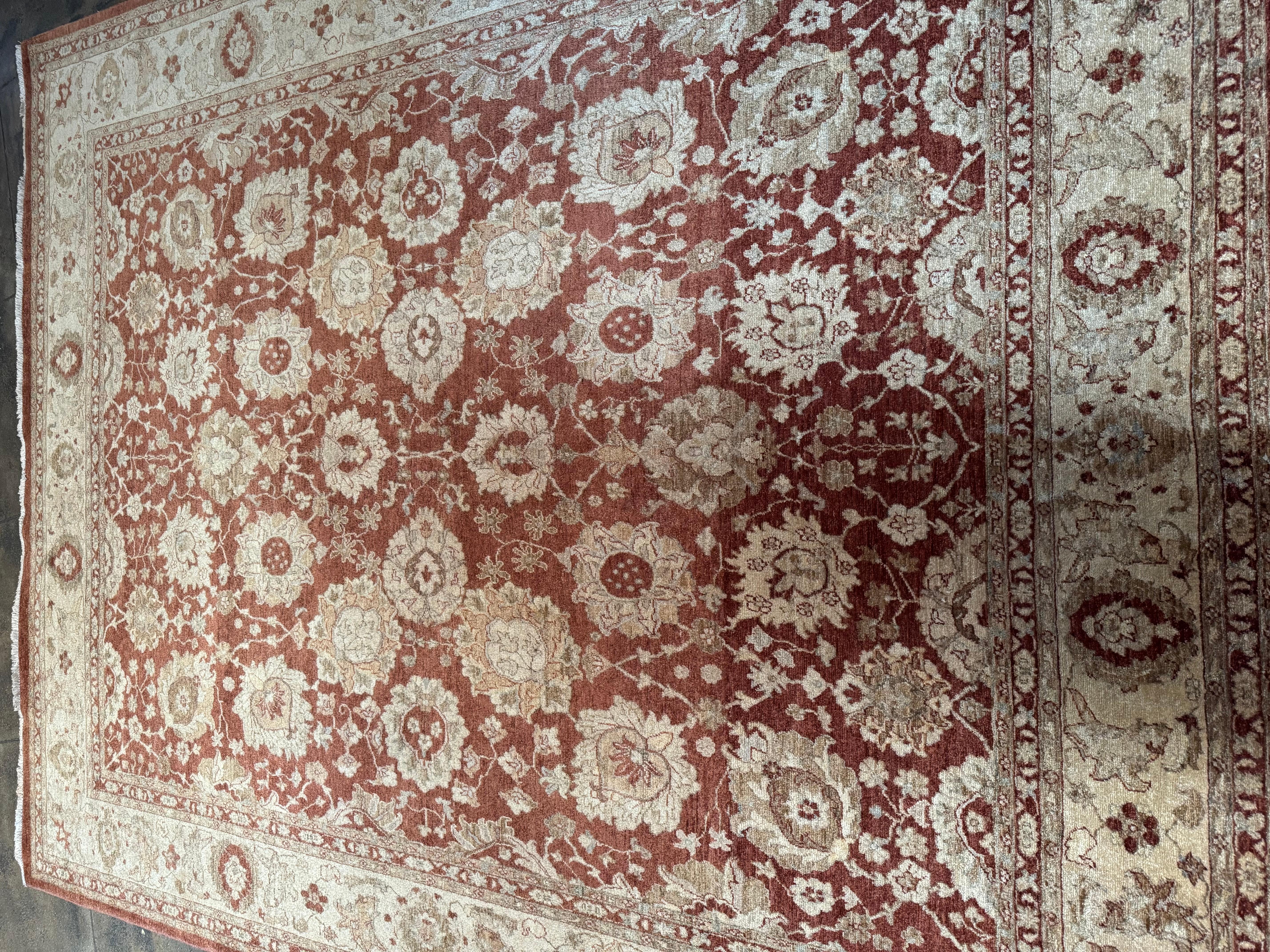 This stunning hand-knotted rug hails from Lahore, Pakistan, a region known for its refined weaving traditions and intricate floral motifs. Featuring a rich rust-red field with elegant ivory and beige florals, this piece beautifully balances warmth