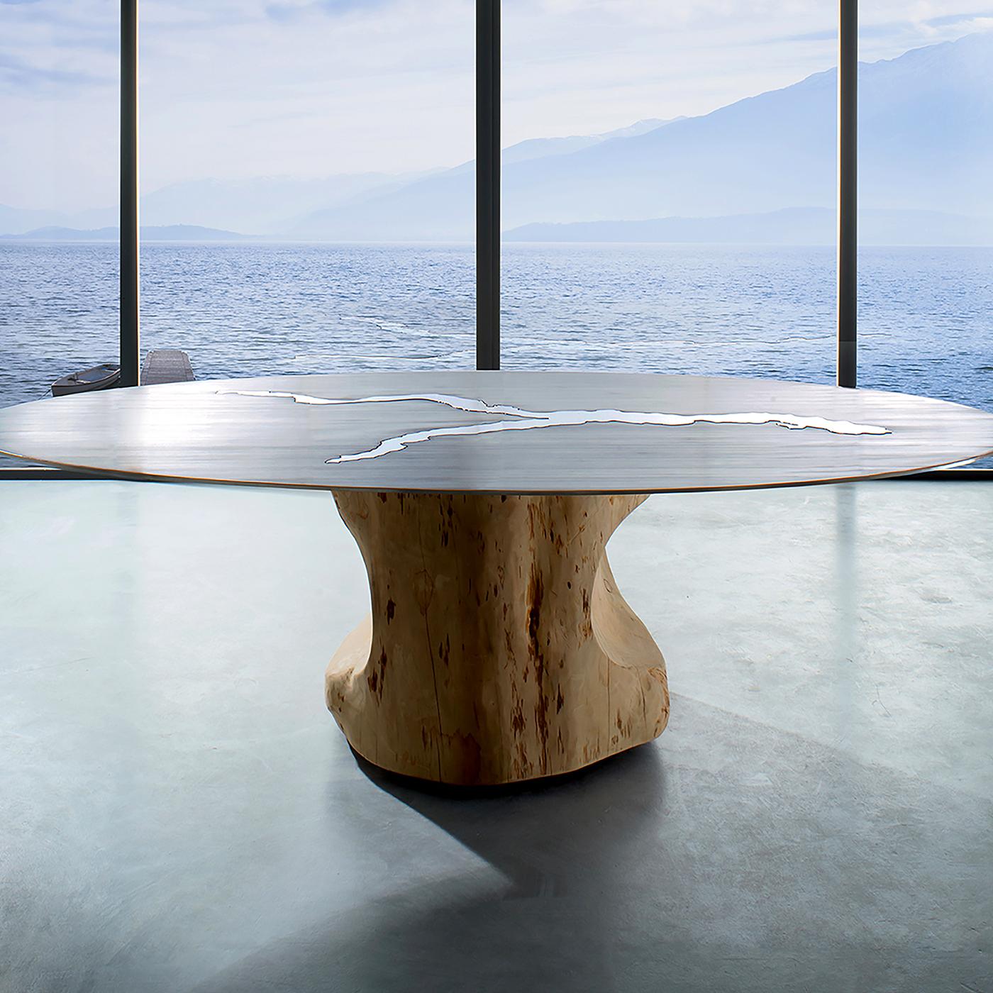 Inspired by the magic allure of Lake Como, this table boasts the charming silhouette of the lake in mirror finish on the satin-finished top. Made of stainless steel, the top is supported by a smooth tree log hailing from the mountains surrounding