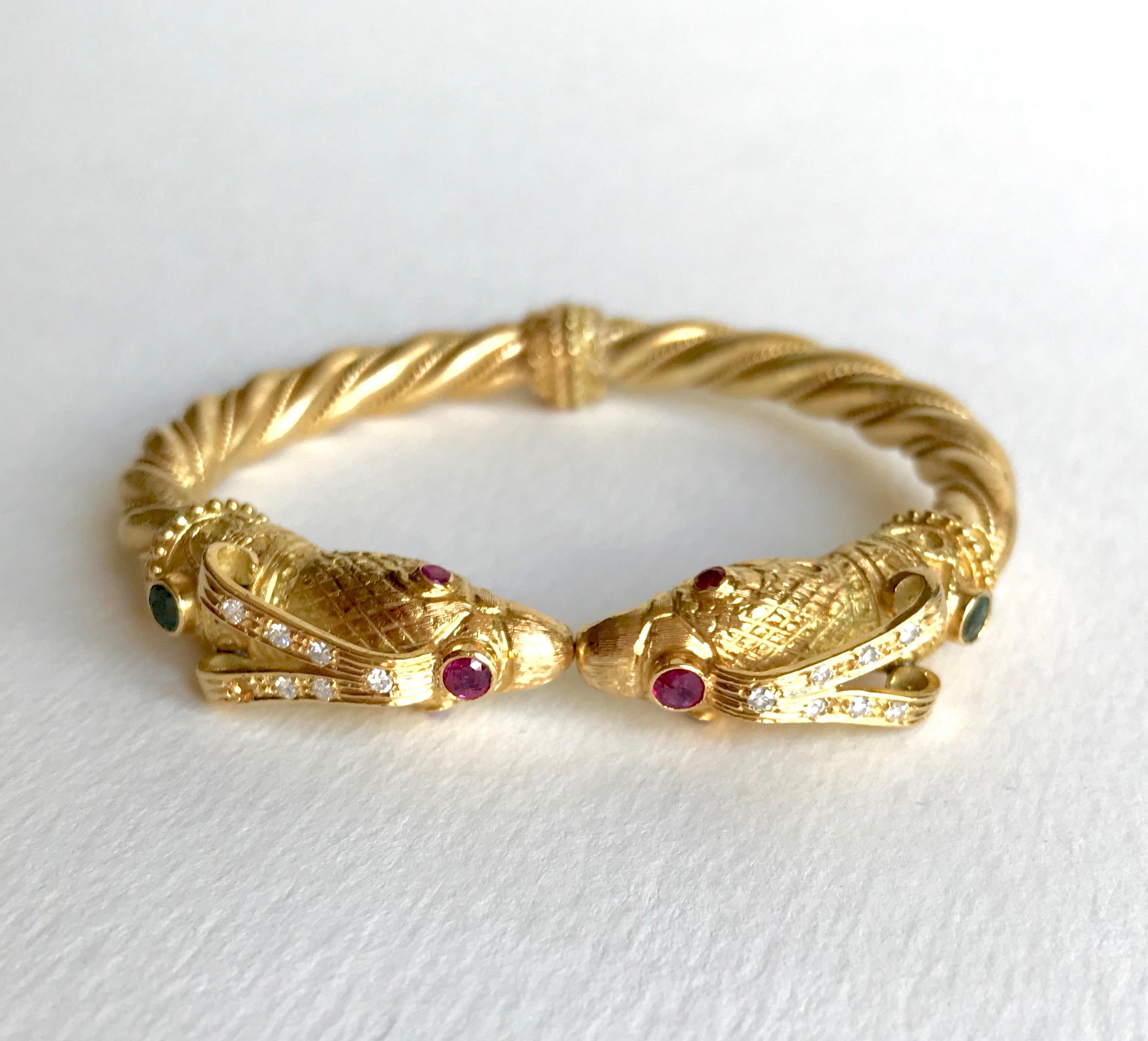LALAOUNIS 18 carats yellow Gold, Emeralds, Rubies and Diamonds.
18 Carat yellow Gold LALAOUNIS folding hard Bracelet featuring two Eagle Heads facing each other, setting an Emerald, a Ruby ​​and seven Diamonds on each Top, and two Rubies for each