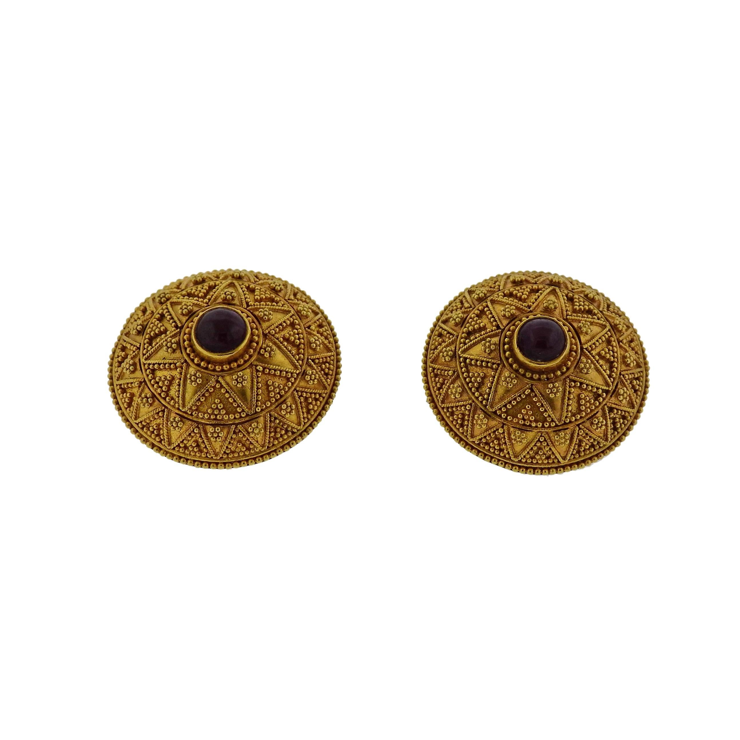 Pair of 18k yellow gold earrings, crafted by Greek designer Ilias Lalaounis, set with ruby cabochon in the center. Earrings are 23mm in diameter and weigh 20.2 grams. Marked Greece, 750, H 17, Maker's mark.