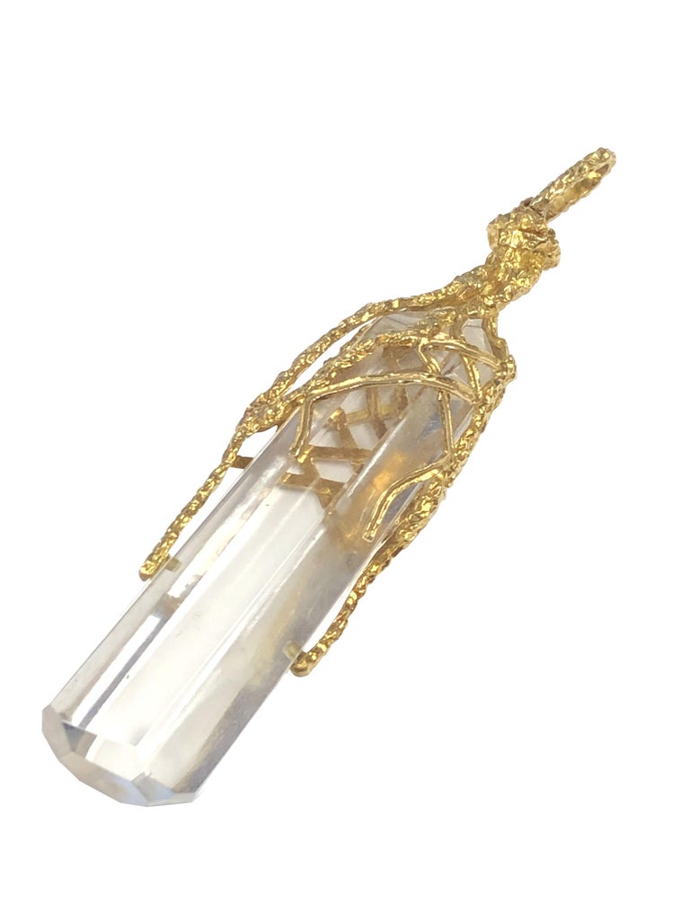 Circa 1980s Ilias Lalaounis, Brutalist, Modernist style 18k Yellow Gold and Rock Crystal Large and Impressive Pendant, measuring 4 inches in length and 3/4 inch in diameter. A solid Clear Faceted Rock Crystal over set with heavy textured Gold. 