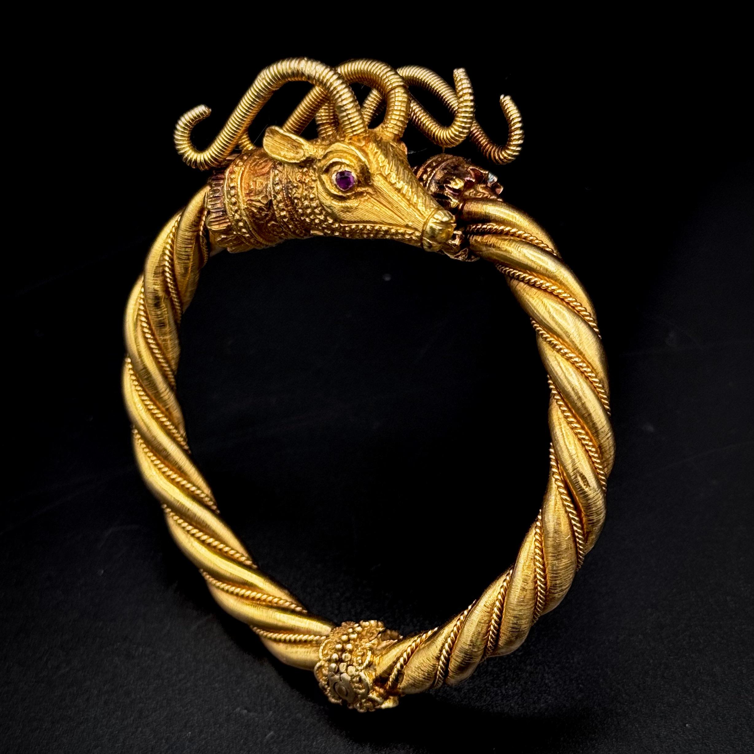 Lalaounis vintage double ram’s head ruby bangle bracelet in 18kt yellow gold, Greece, 1970s. This hinged open bangle is modelled as two opposing textured and carved ram heads accented with circular-shape ruby eyes, each issuing a twisted neck