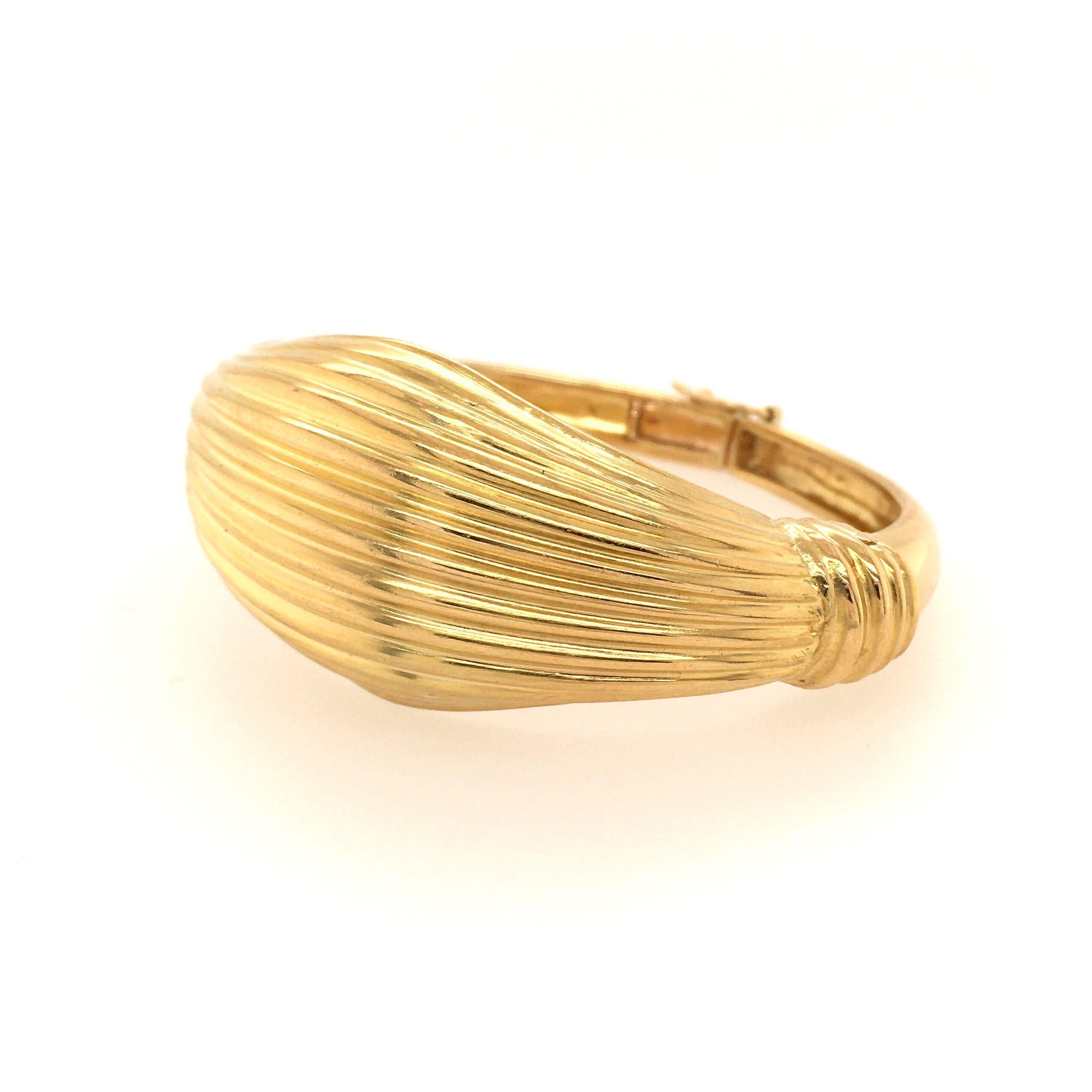 A 22 karat yellow gold bracelet. Lalaounis. The hinged bangle designed as  fluted gold bombe panel, tapering to a narrower band. At widest bracelet measures 1 1/4 inches, inside measurement is approximately 7 inches, gross weight is approximately