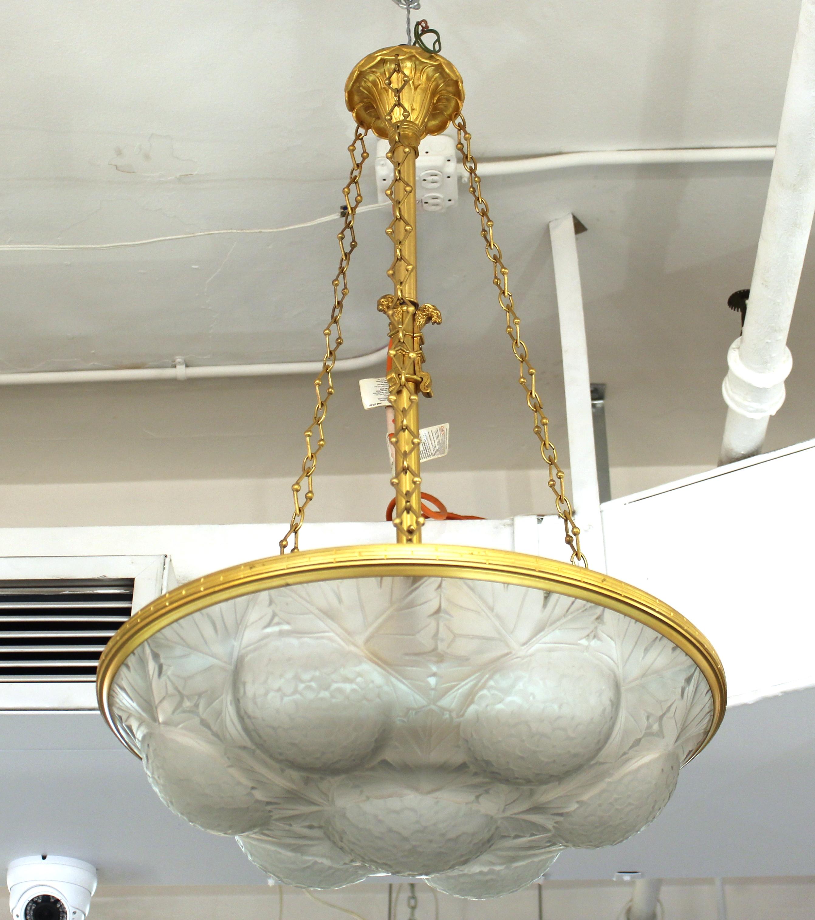 French Lalique attributed Art Deco frosted art glass pendant chandelier, with seven floral motif roundels interspersed with foliate decoration and gilt metal chains and stem with ornate rams heads. Measures: 31