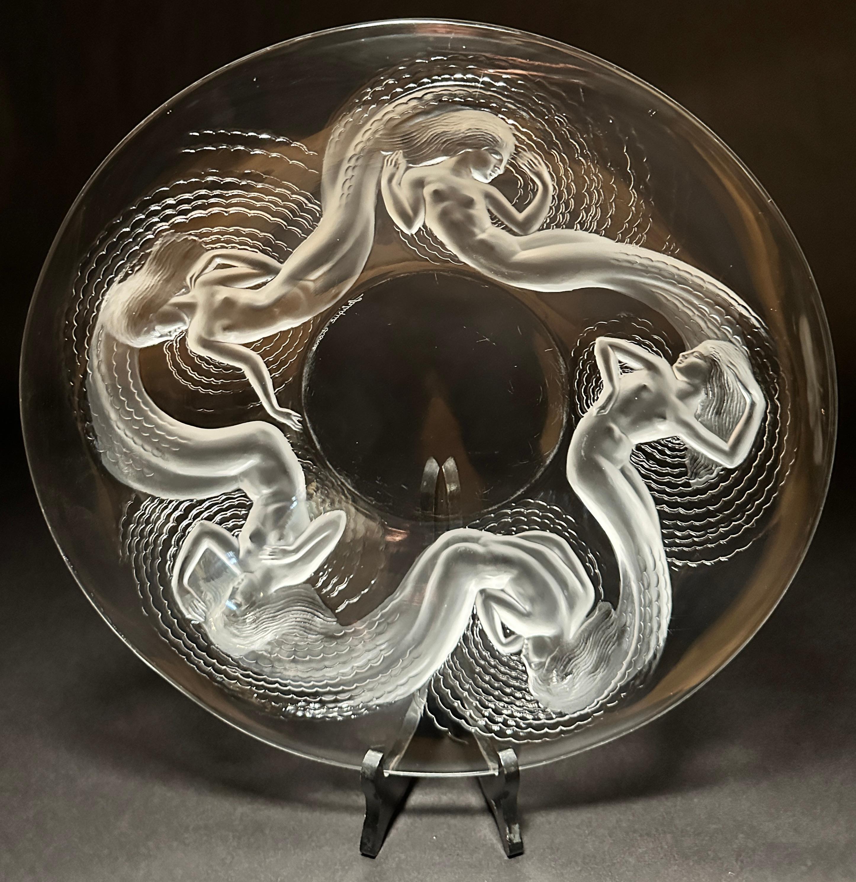 Lalique clear and frosted shallow bowl or charger in 'Calypso' design. Signed 'Lalique France' on bottom. It features frosted opalescent relief nudes, nymphs or mermaids. 
Stand not included.