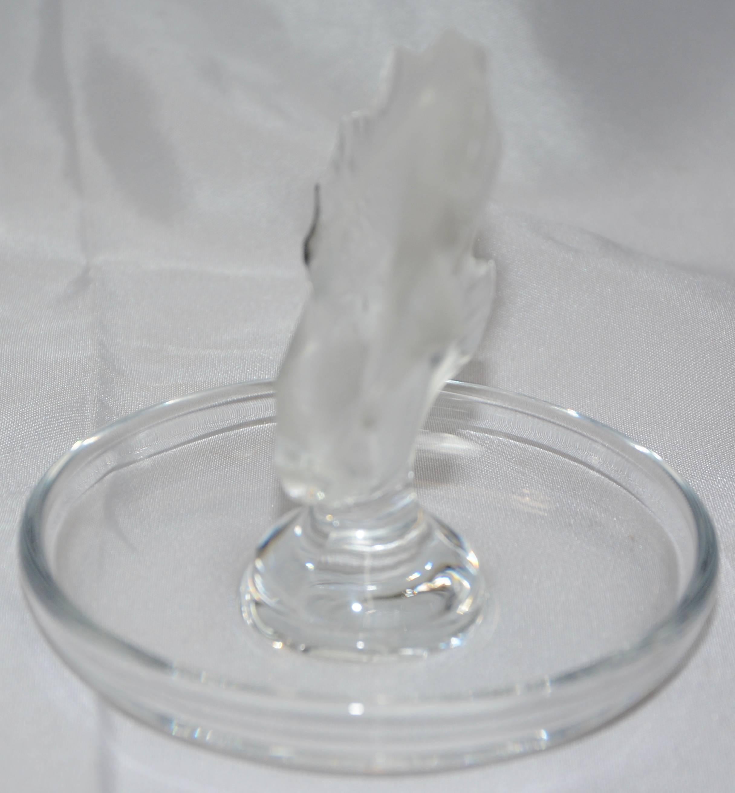We are offering a Lalique of France Koi fish finished in their well-known satin glass. He is jumping from a clear crystal ring dish. The piece is signed in cursive on the bottom.