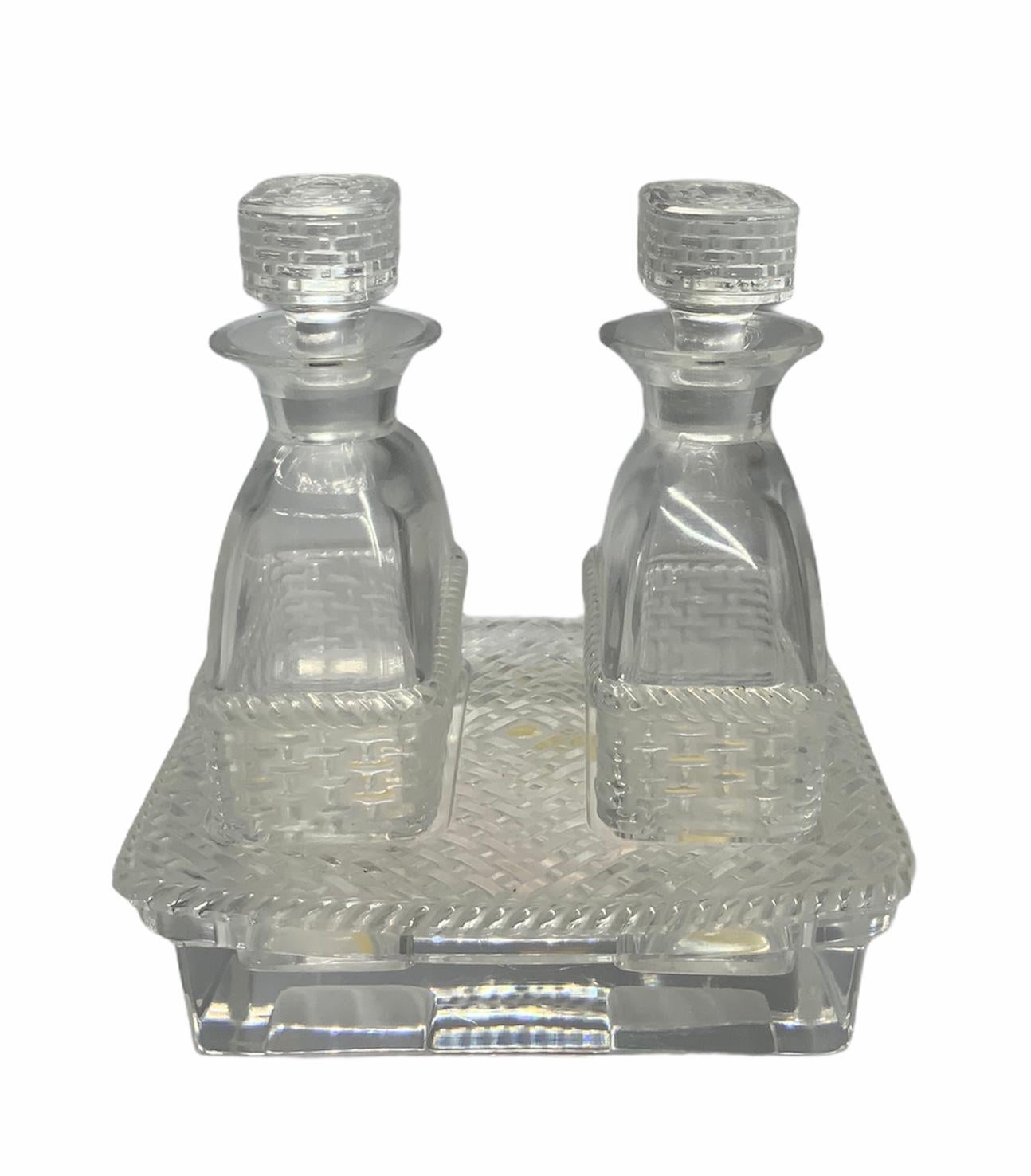 This set of oil and vinegar crystal bottles are decorated with a basket weave design in the lower part of them and also in the stoppers. The top of the tray follows the same pattern. Under the tray is signed Lalique.