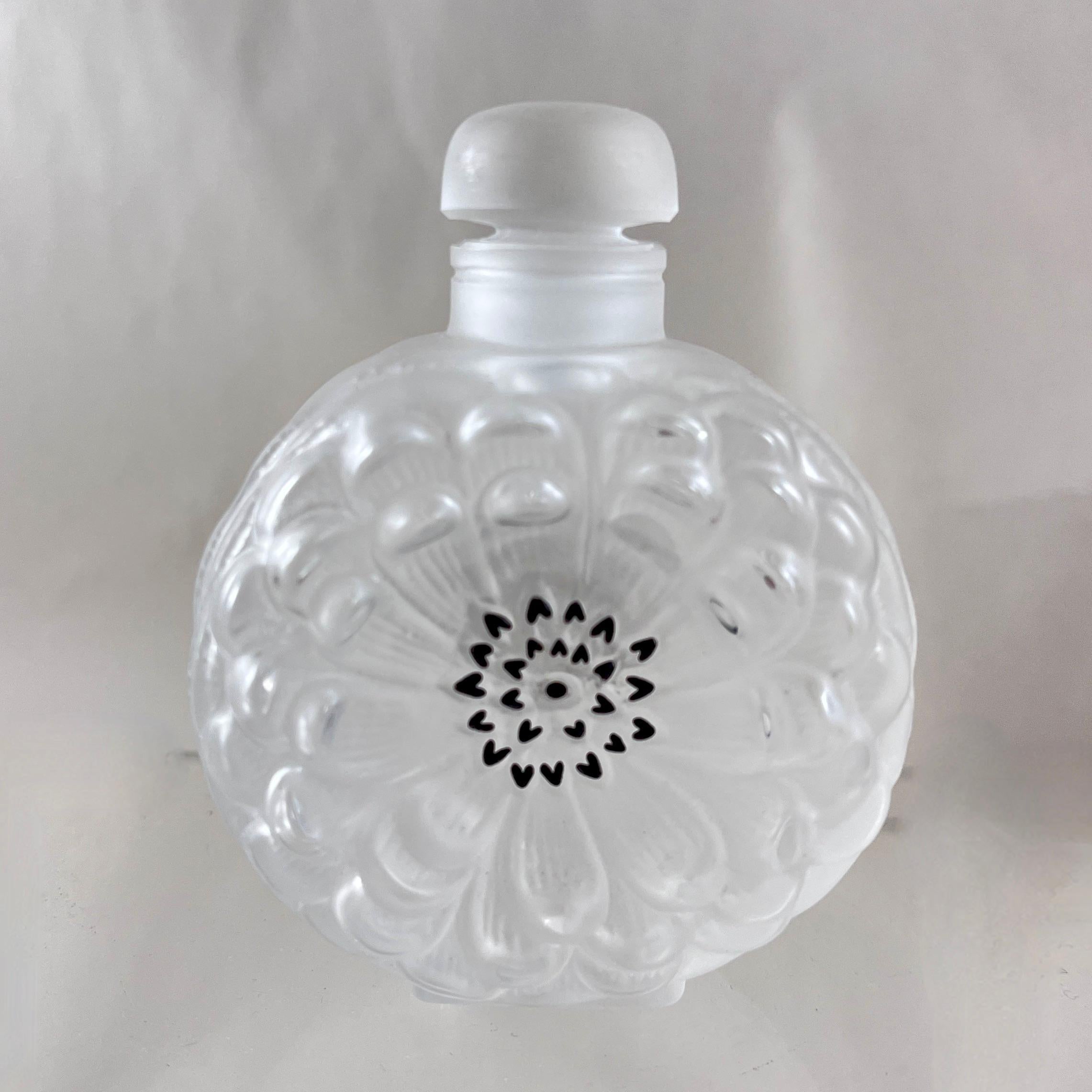 Da Lalique, Francia, l'iconico flacone del profumo Dahlia, circa all'inizio degli anni Ottanta.

Gli accenti smaltati neri evidenziano i fiori di Dalia presenti su entrambi i lati della bottiglia dalla forma arrotondata.

Stampato in una miscela di