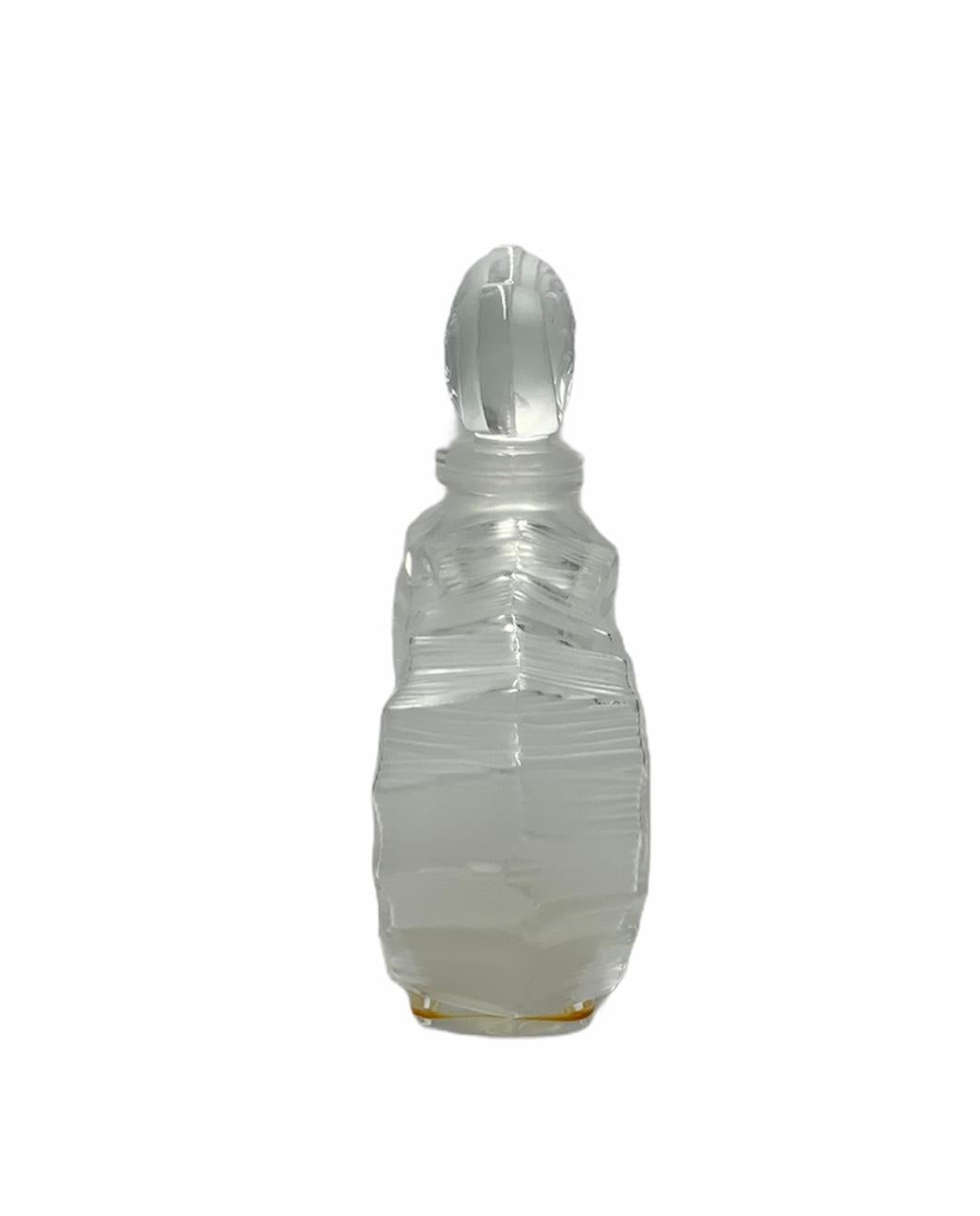 This is a Lalique frosted and clear crystal Deux Hearts perfume bottle. The bottle is shaped as two overlapping hearts with scalloped borders and adorned with engraved scrolls and hearts. Also, the stopper is shaped in the same way.