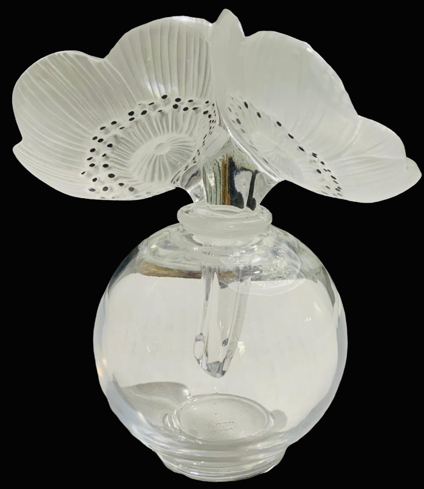 This is a Lalique clear and frosted crystal double anemones large flowers vase. It depicts a bouquet of two anemones flowers as the stopper of a clear rounded vase. Black enamel covers some dots in the center of the flowers. The anemone flower