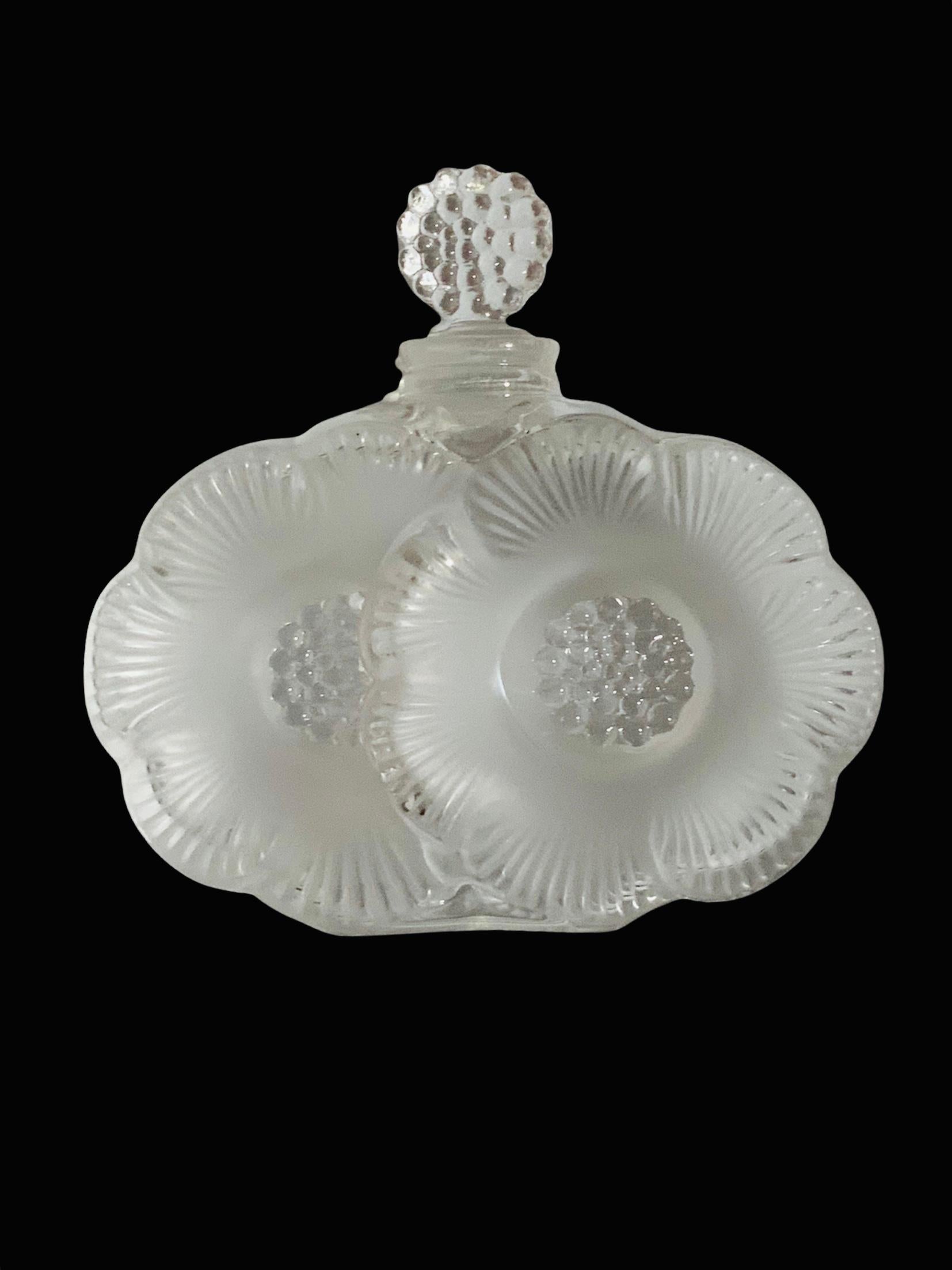 This a Lalique Crystal Deux Fleurs Anemone “petite” perfume bottle. It depicts two frosted/clear Anemone flowers. The Anemone flower symbolizes anticipation, fragility or forsaken love. Below the bottle, it is the acid etched signature of Lalique,