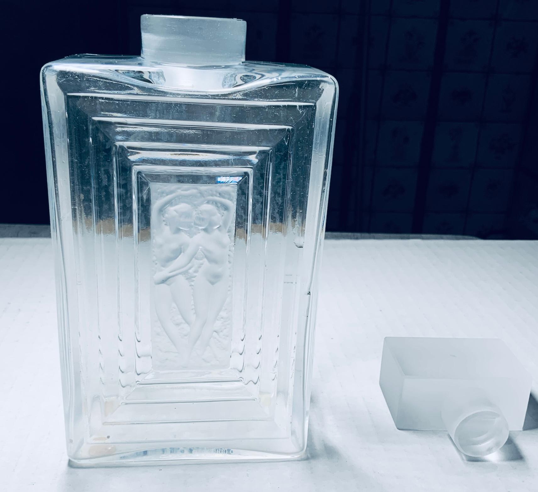 This is a Lalique Crystal Duncan No.3 perfume bottle. It is a clear and frosted crystal rectangular bottle that depicts two nudes female dancers in the front and back of it framed with smaller to bigger rectangular border. The stopper is shaped as a