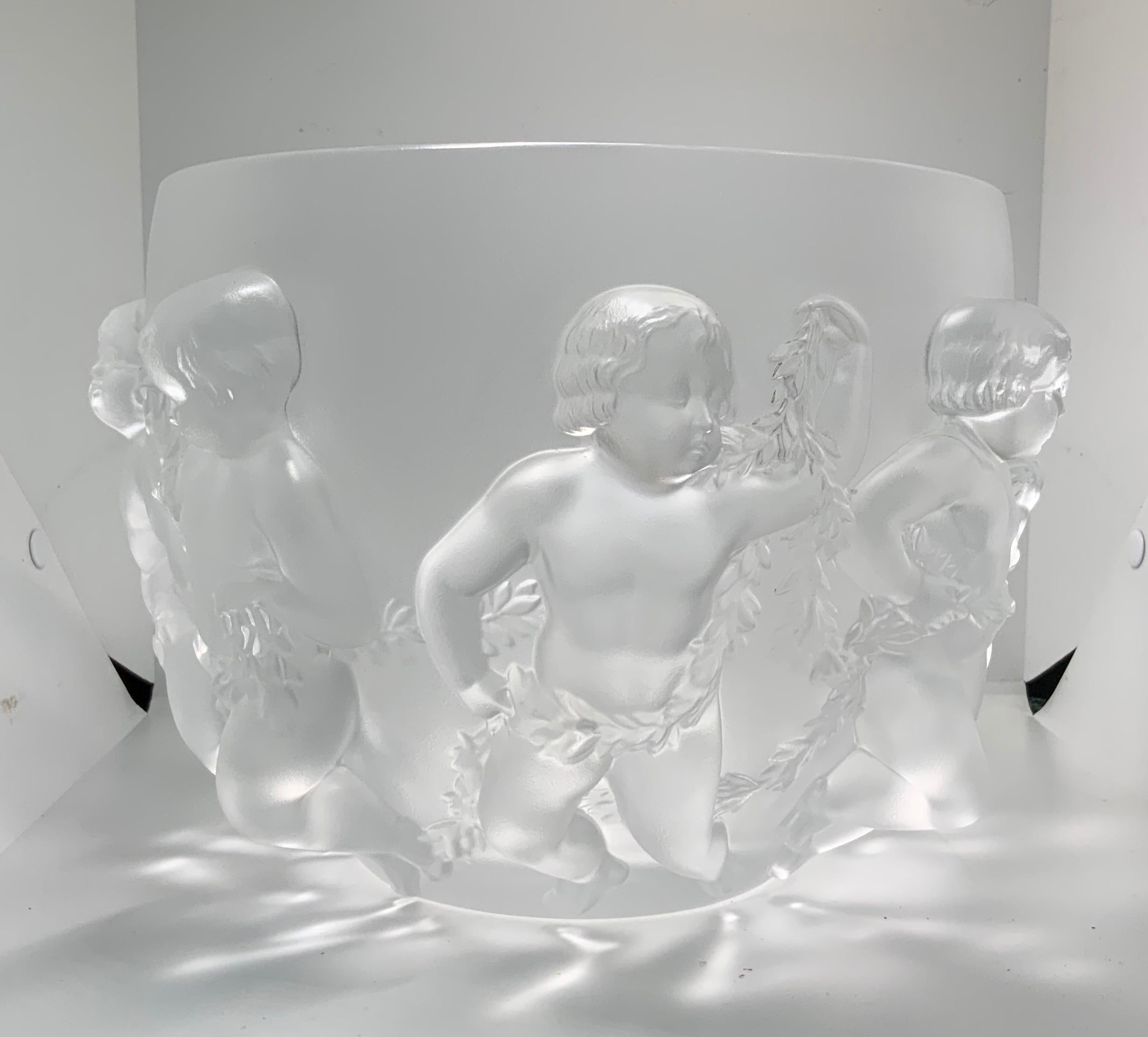 This is a Lalique frosted crystal “ Luxembourg “ large round bowl. It depicts a relief of playful cherubs that are joined together by holding a garland of laurel leaves. Below the base. It is etched Lalique encircled R,France.