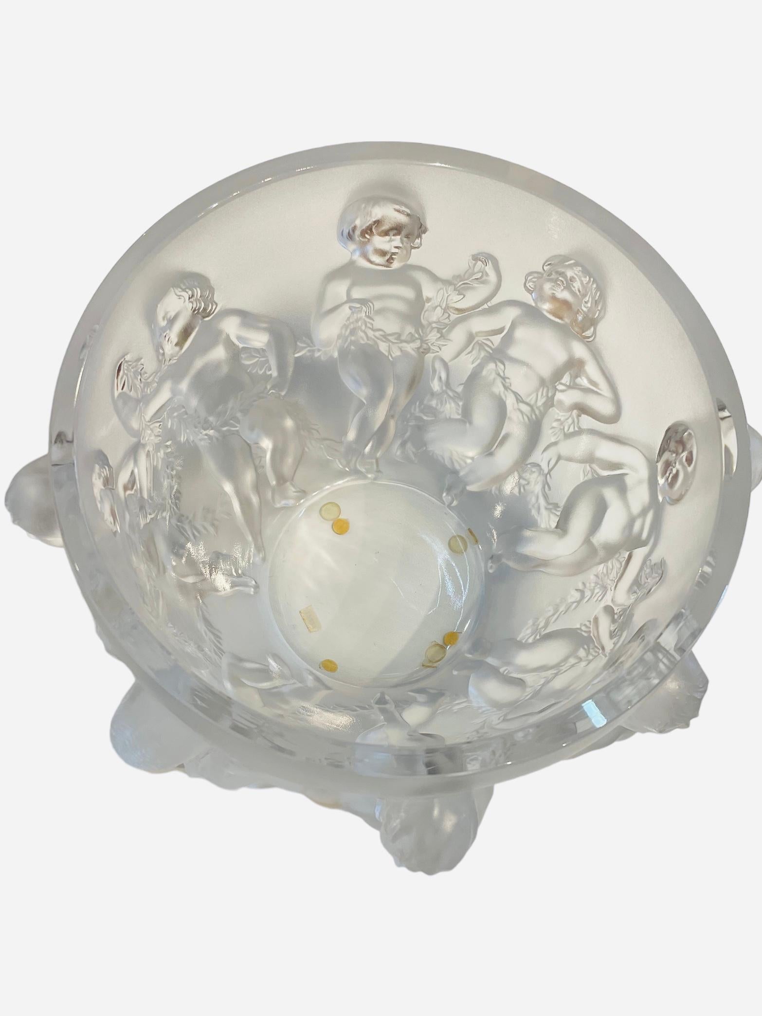 This is a Lalique frosted crystal “ Luxembourg “ large round bowl. It depicts a relief of playful cherubs that are joined together by holding a garland of laurel leaves. Below the base, It is etched Lalique encircled R,France.