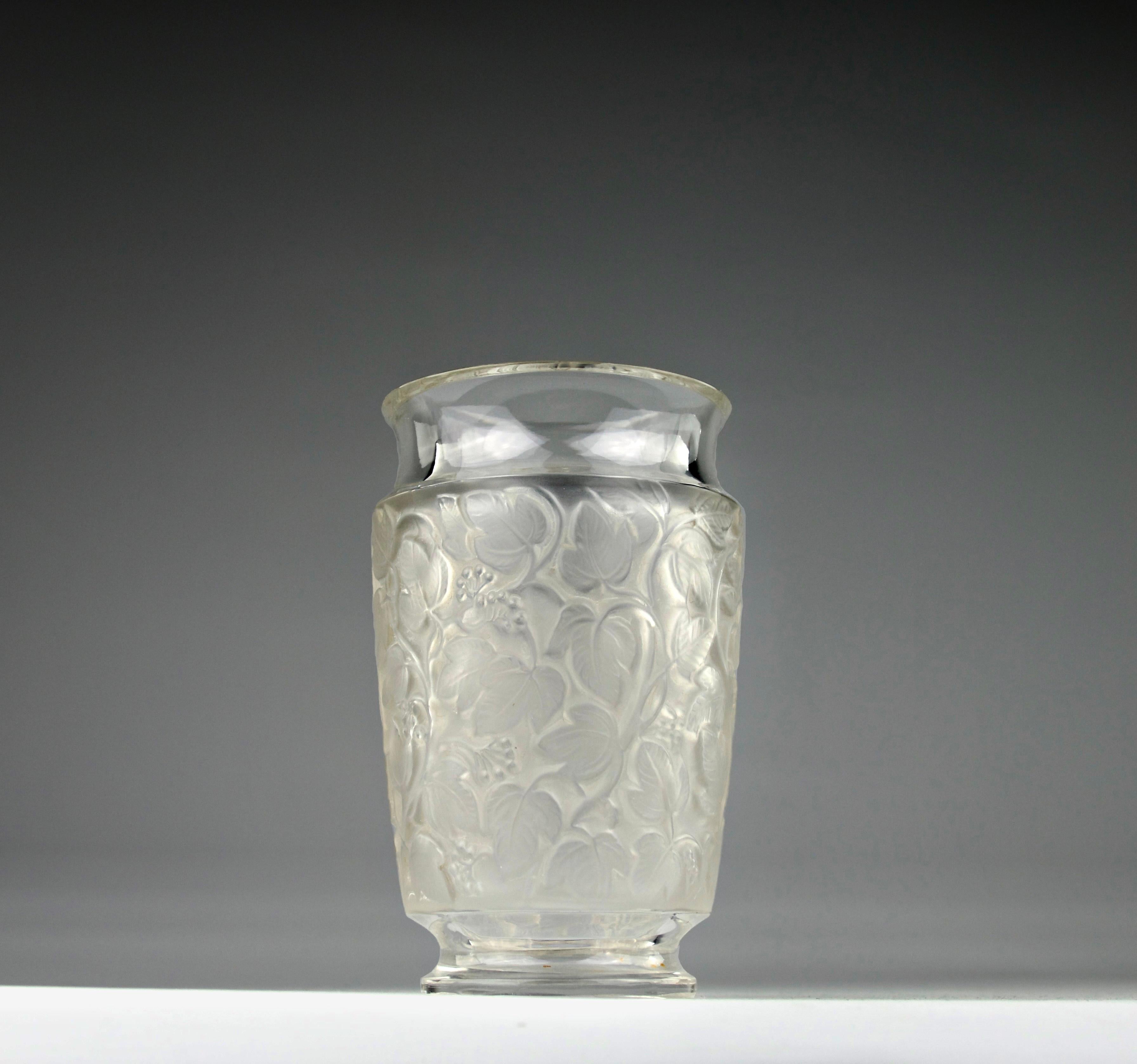 Beau vase Deauville créé par René Lalique avec des décorations de vignes oxydées. Signé Lalique.

En très bon état. Légères traces d'utilisation. A été recoupé par un maître artisan verrier.

Dimensions en cm (H x P) : 14.5 x 9

Expédition