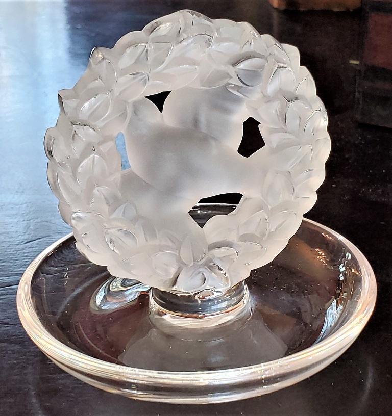 Presenting a beautiful Lalique dove wreath pin or ring dish.

Made by Lalique – France circa 1960.

This is a Classic Lalique piece with opalescent glass with an embellished wreath with central dove.

Fully signed and in excellent