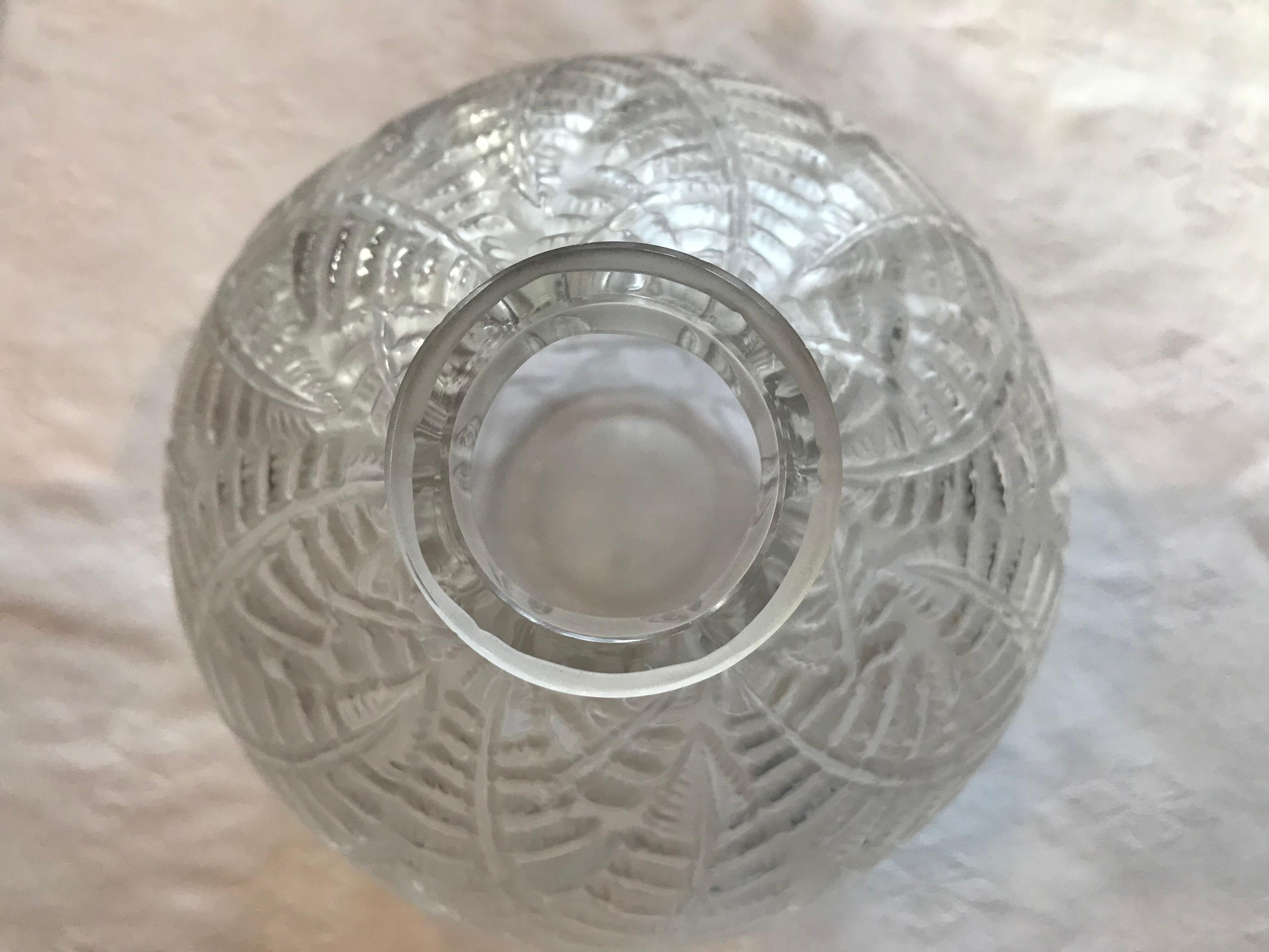 The naturalistic theme of ferns is pressed into a Classic, round 8” Lalique souffle-moule vase. Frosted clear glass. 

This exquisite round vase is also called “fougeres” or bracken.

Signed “R. Lalique France”. Model 996. Production of this