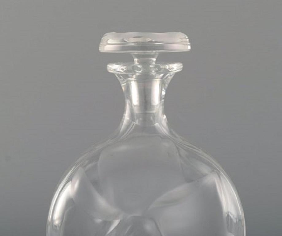 Flacon Lalique en verre d'art transparent et dépoli, années 1980.
En parfait état.
Signature incisée.
Mesures : 17 x 9,5 cm.
