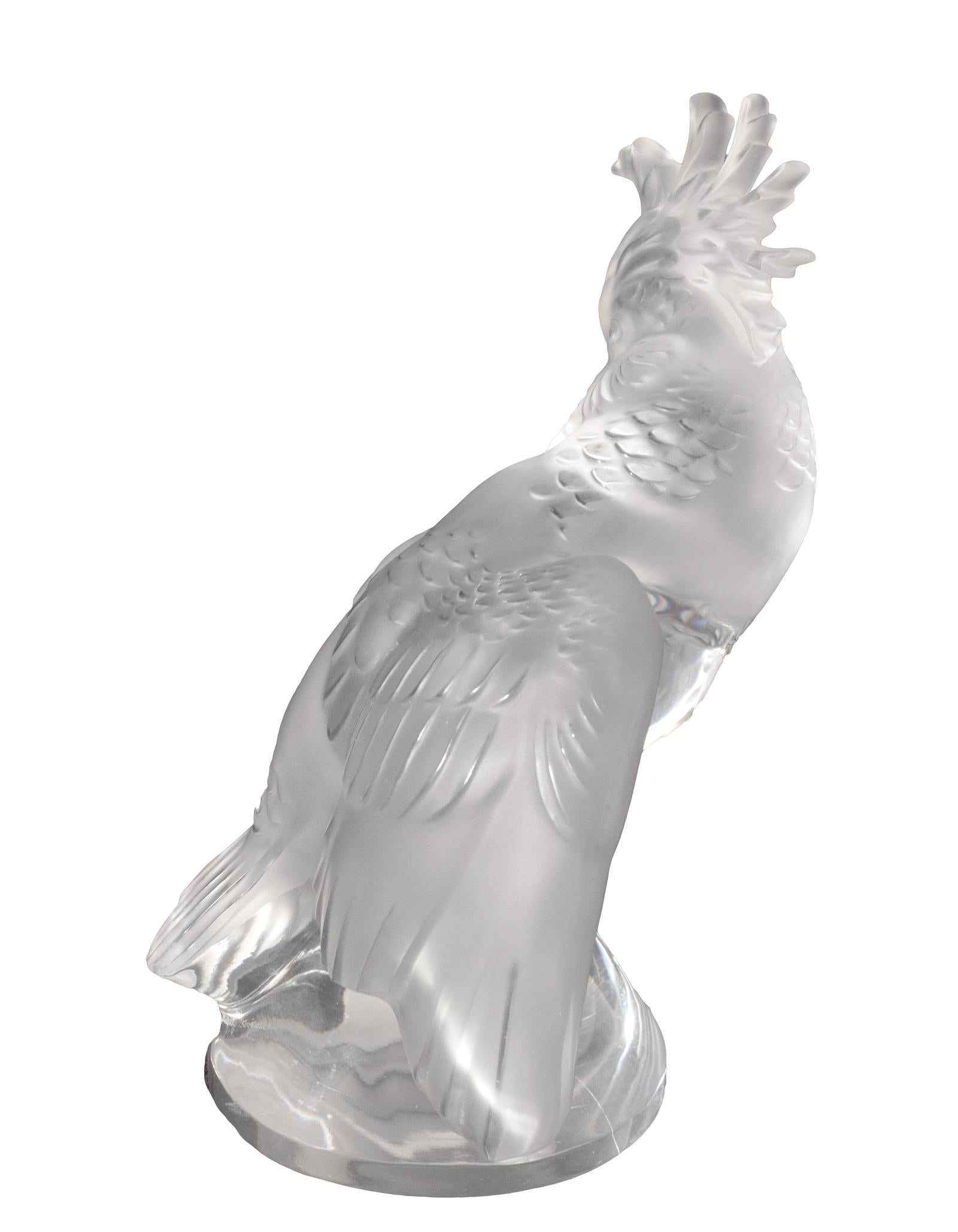 Frosted and clear crystal figure of a cockatoo on a conical perch, wings are partially spread and his head is turned back; etched signature reads 