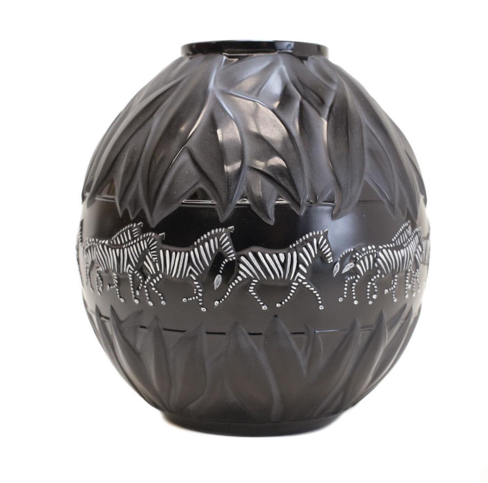 Vase en cristal d'art et émail Tanzanie noir de Marie-Claude Lalique, 1991. Des feuilles de satin ornent le haut et la base du vase, tandis que de charmants zèbres peints à la main galopent sur la bande circulaire. Marqué sur la face inférieure.
 