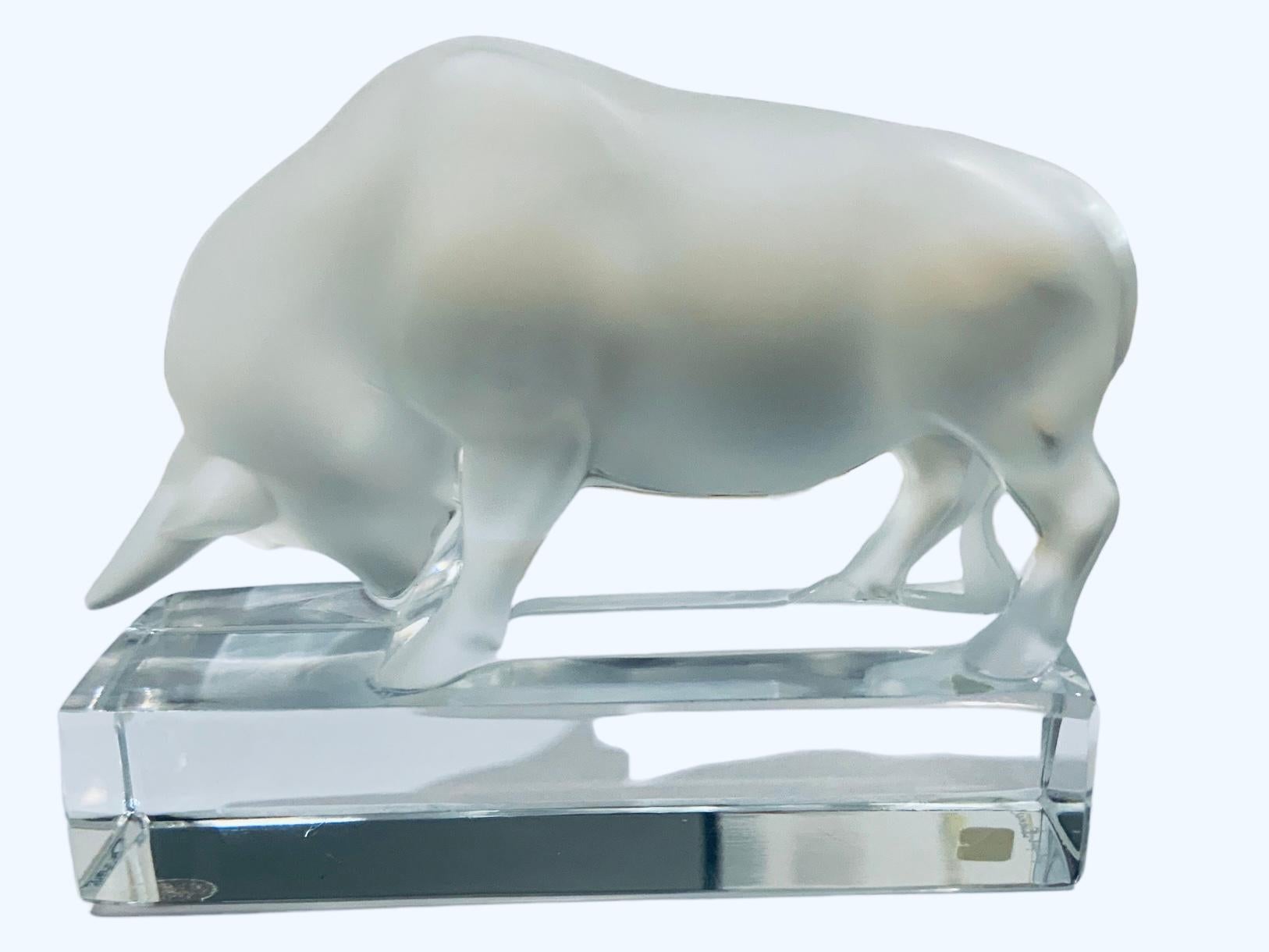 This is a Lalique frosted and clear crystal bull sculpture /figurine paperweight. The strong and stubborn bull is stroking the soil with its strong right frontal leg muscles. Below the rectangular clear crystal base is the acid etched Lalique