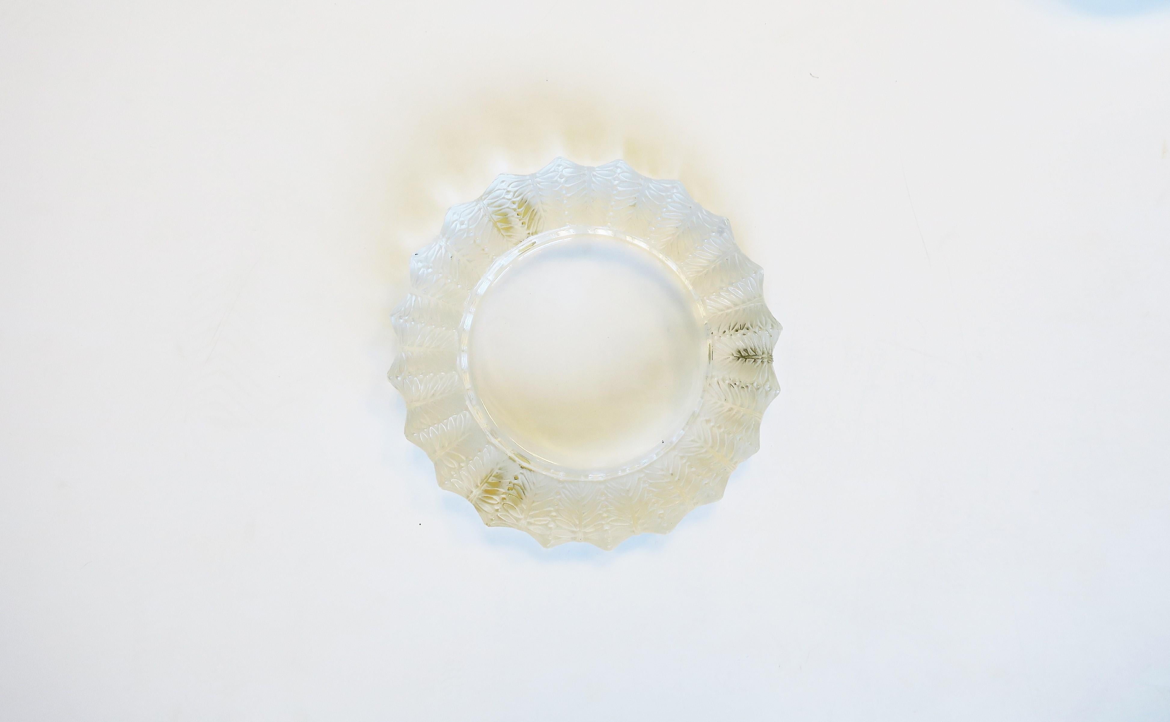 Precioso plato de cristal de Lalique, firmado, con diseño decorativo de hojas y hendiduras alrededor del borde, hacia el siglo XX, Francia. La pieza es del fabricante francés de cristal de lujo Lalique. Fabricado en Francia. Con la marca del