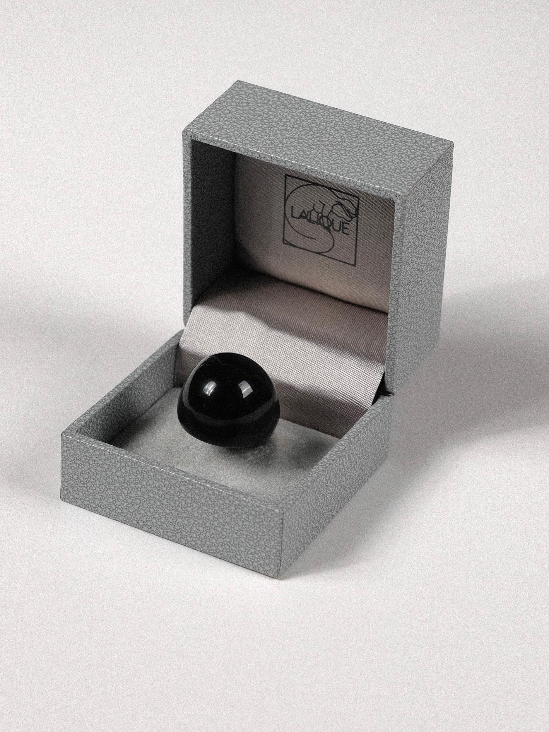 Klassischer und wesentlicher Lalique Gourmande Cabochon Glasring aus schwarzem Glas
Der Ring wurde 1931 von René Lalique entworfen und erinnert mit seiner voluminösen Form und den verschiedenen Farben an die Ära des Art déco. Die Schachtel datiert