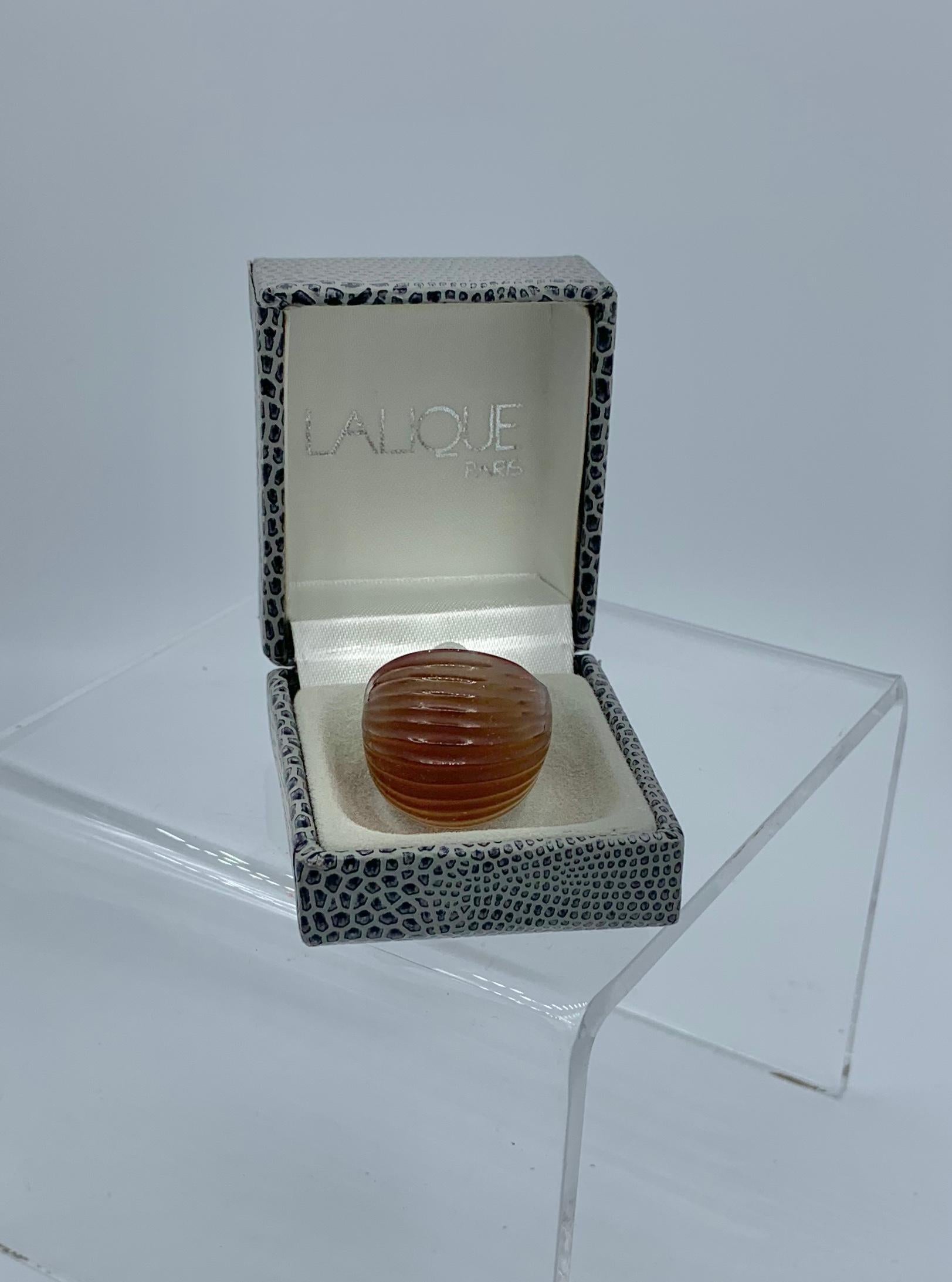This is the 1990s version of Lalique's iconic ‘cabochon’ ring created in 1931.  The glass ring is inspired by the natural shell pattern of the Nerita shell.  The delicately chiseled lines in the dome evoke the form of the Nerita shell.  The color of