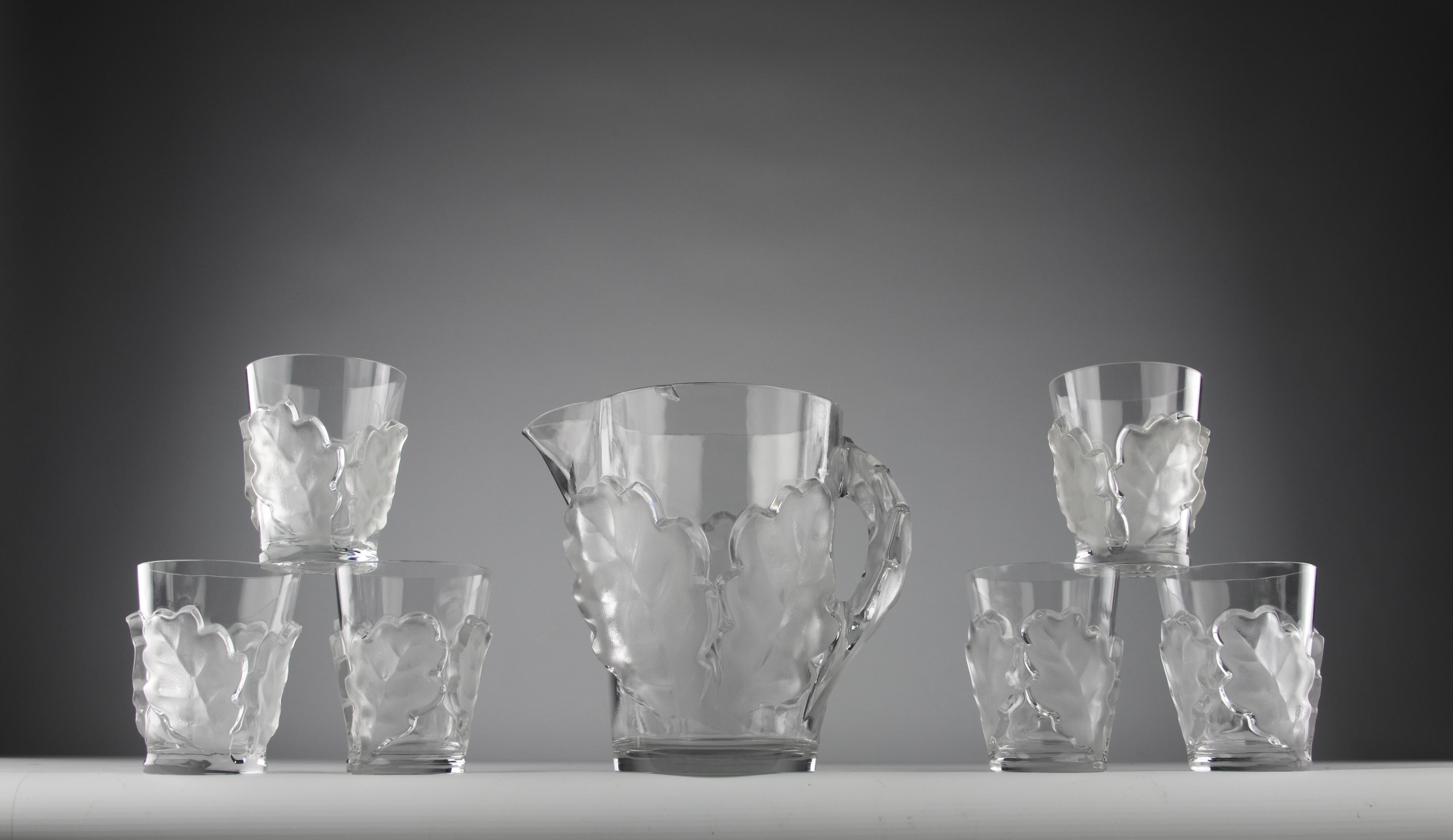 Magnifique service en cristal à feuilles de chêne créé par Marc Lalique pour la Maison Maison en 1950. 

En bon état. Un éclat à noter sur le bord de la carafe.

Dimensions en cm ( H x L x l ) et ( H x D ) :
- Carafe 21,7 x 24 x 15,8
- Verre 11,8 x
